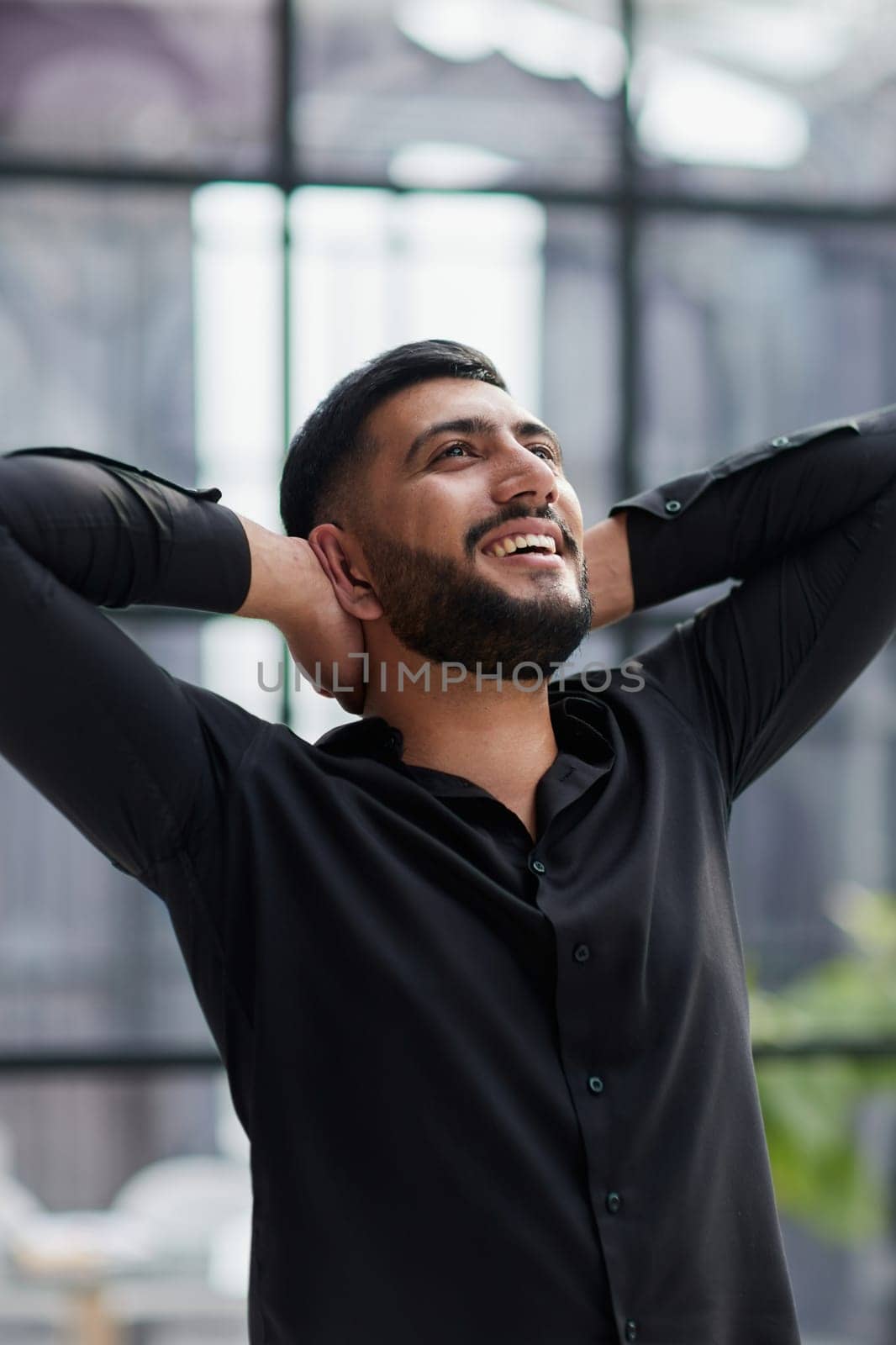Portrait of relaxed businessman in modern office.Business young man relax after work of office window with business district view.
