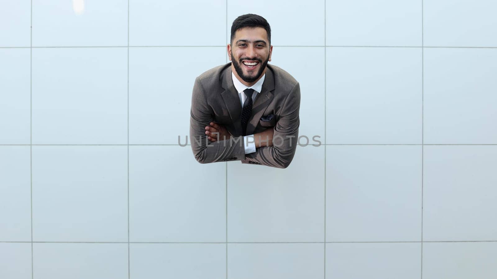 Handsome smiling business man in a suit standing with his arms crossed. View from above
