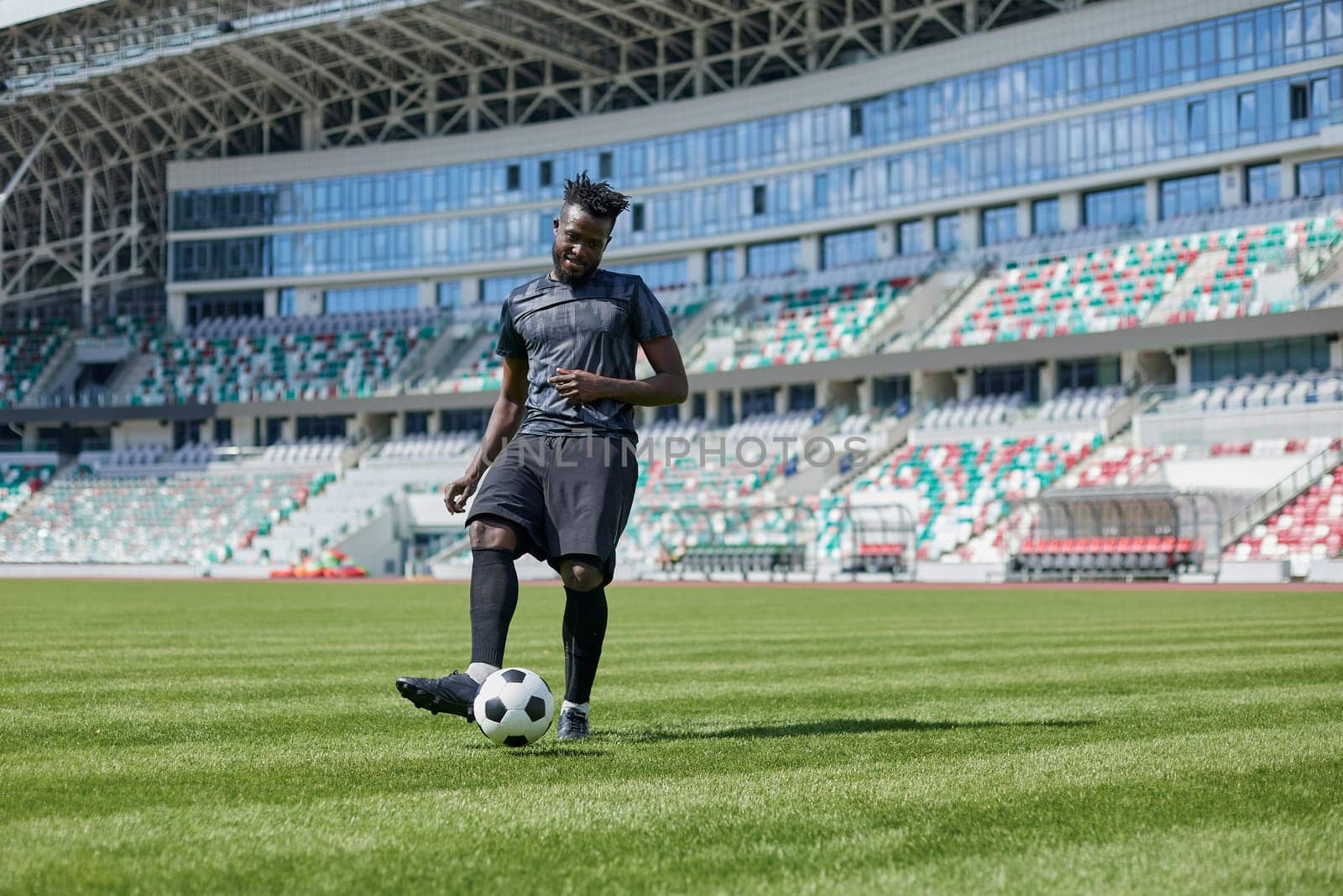 African American man playing football on the stadium field. A man runs with a soccer ball across the field.