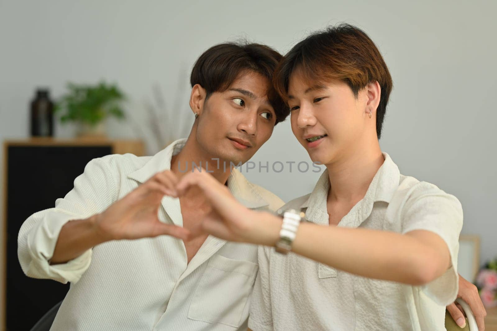 Affectionate same sex male couple making heart with their hands. LGBT, love and lifestyle relationship concept by prathanchorruangsak