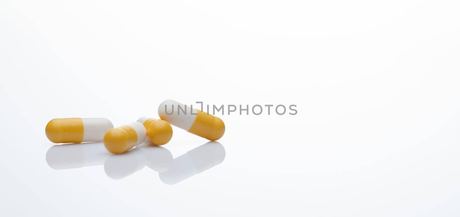 Yellow-white probiotic capsule pill on white background. Probiotic supplement. Gut health. Dietary supplements. Probiotics for a healthy gut. Lactobacillus acidophilus and Bifidobacterium animalis. by Fahroni