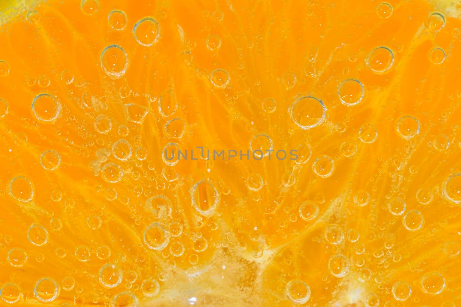 Slice of orange fruit in sparkling water. Orange fruit slice covered by bubbles in carbonated water. Orange fruit slice in water with bubbles. Close-up, macro horizontal image. by roman_nerud