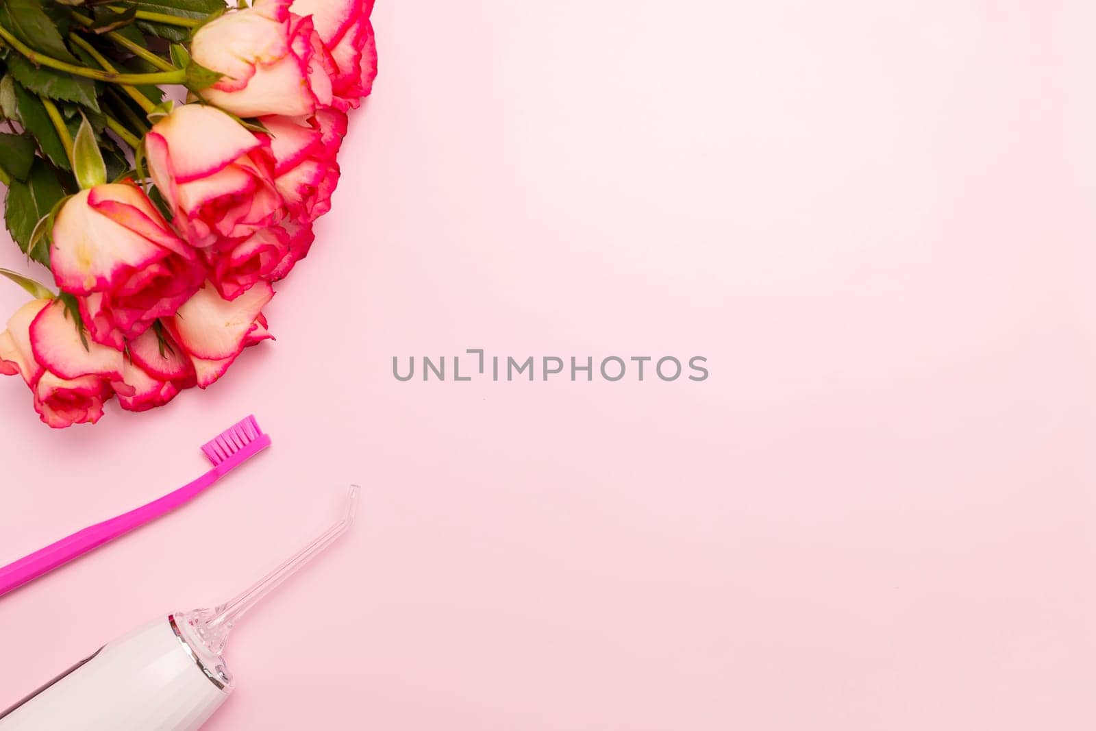 Happy International Dentist Day rose flowers, oral teeth irrigator, toothbrush on pink background mockup. Dental care. Greeting card for professional holiday. Copy space, horizontal. by netatsi