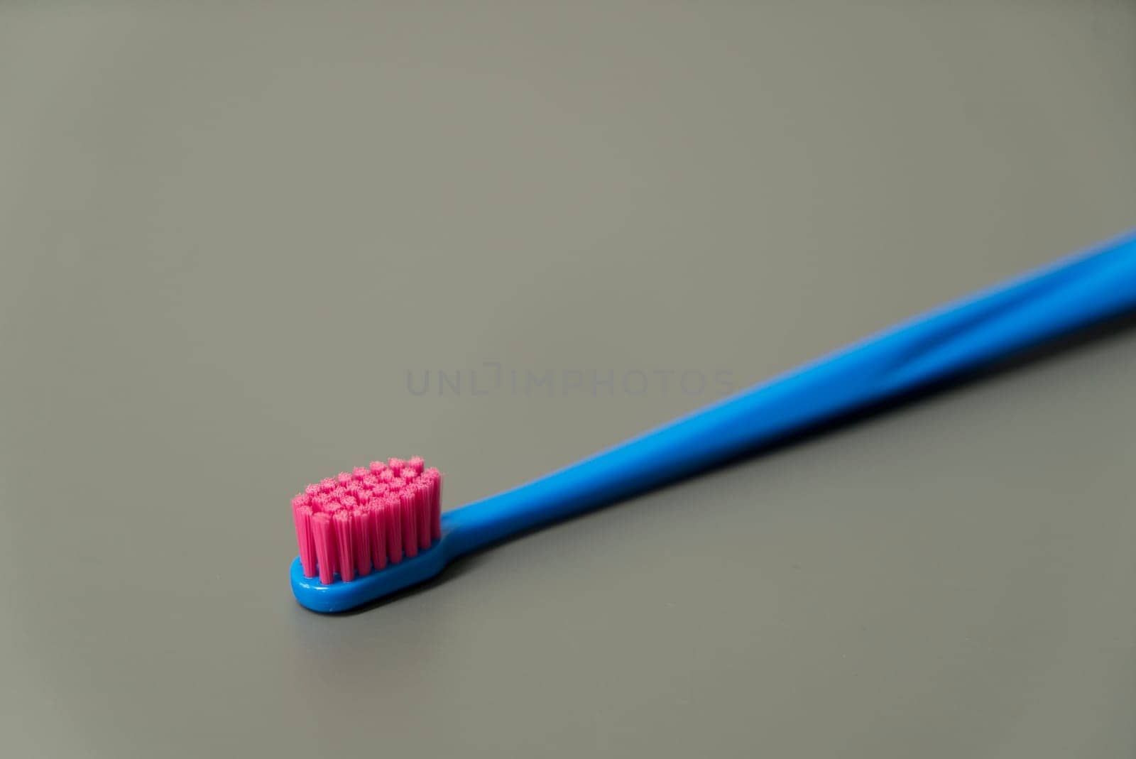 Plastic toothbrush on grey background. Blue and pink color brush. Healthcare, hygiene for teeth.