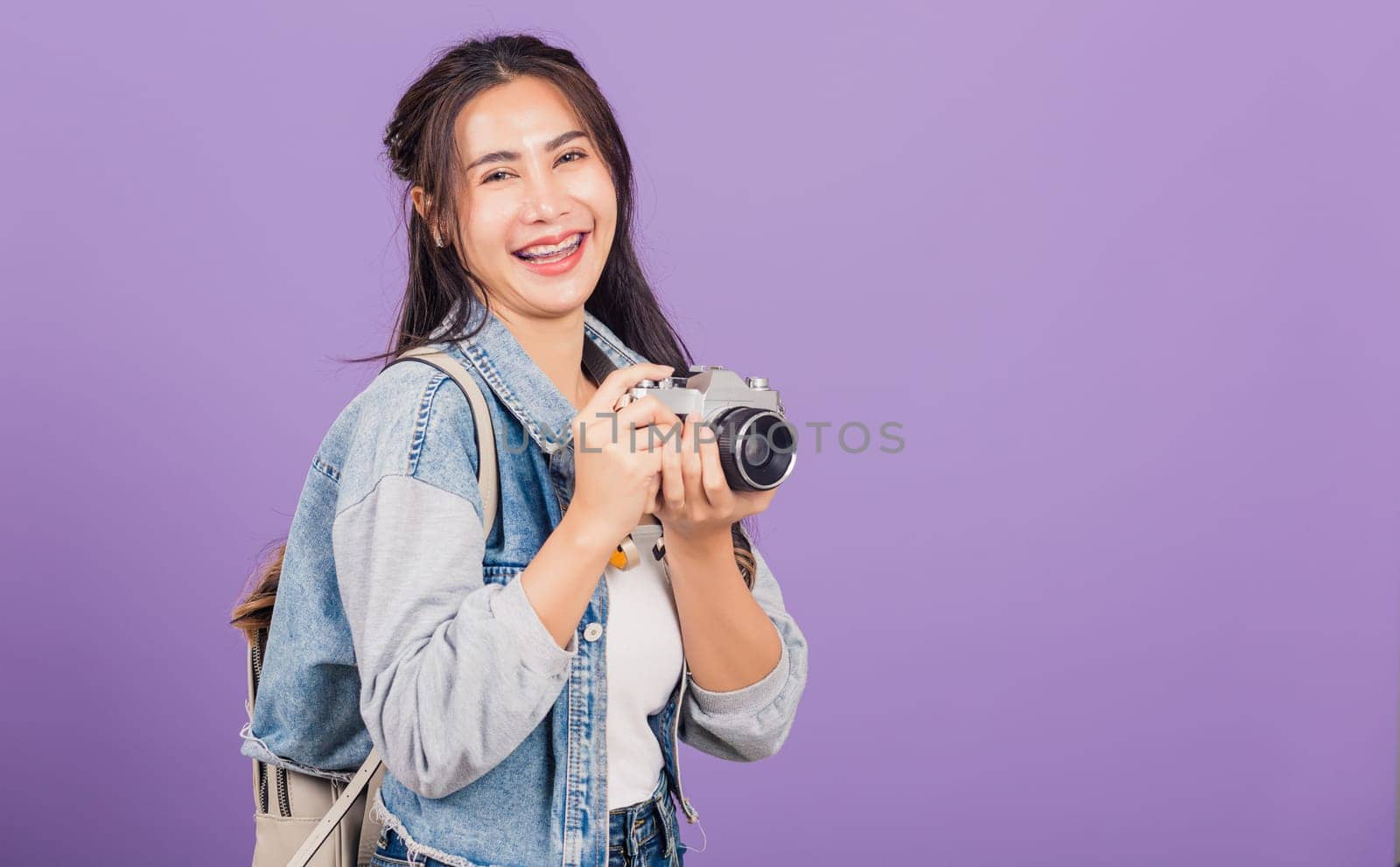 woman smiling excited wear denims and bag holding vintage photo camera by Sorapop