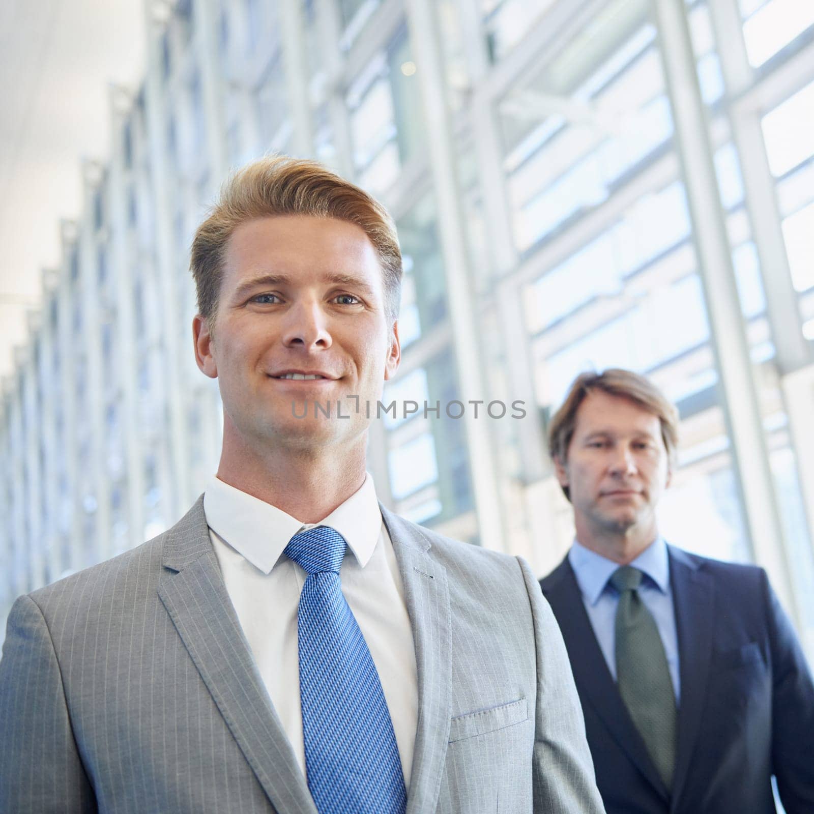 Rising young talent of the company. Portrait of a young businessman with his senior colleague standing behind him