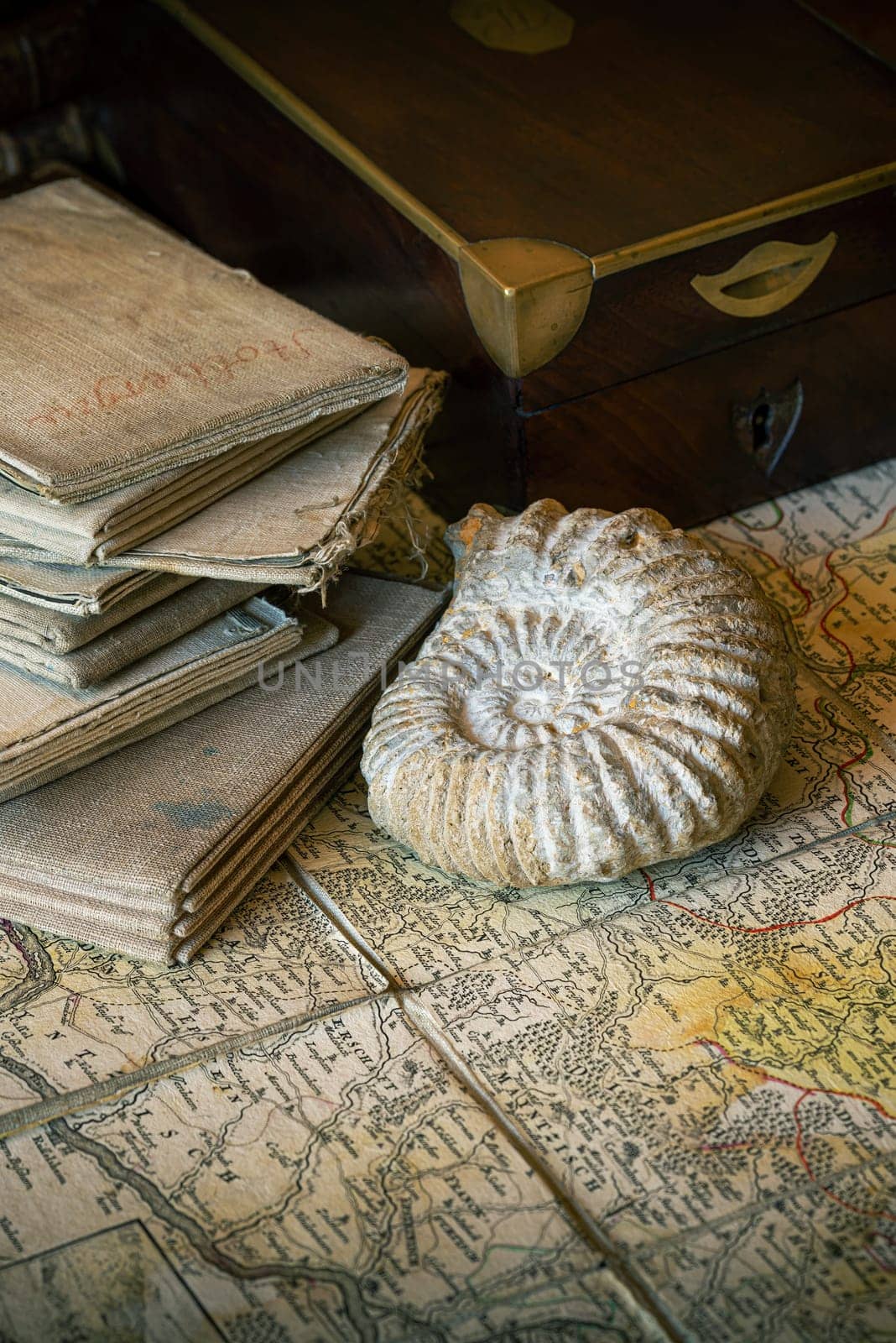 Ancient topographic maps on a table, with an old wooden box and an amonite