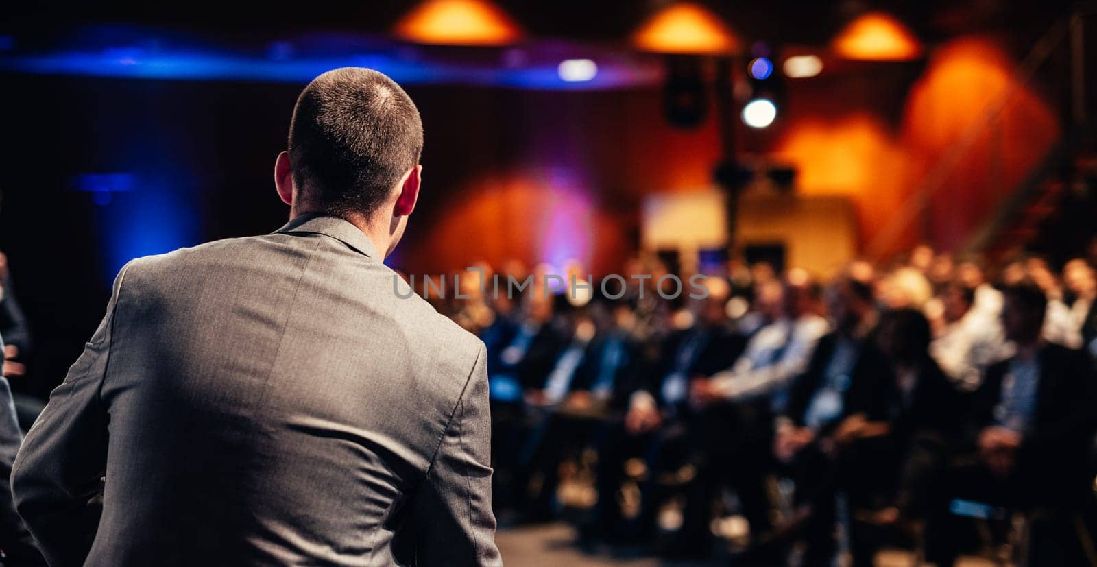 Speaker giving a talk on corporate business conference. Unrecognizable people in audience at conference hall. Business and Entrepreneurship event.