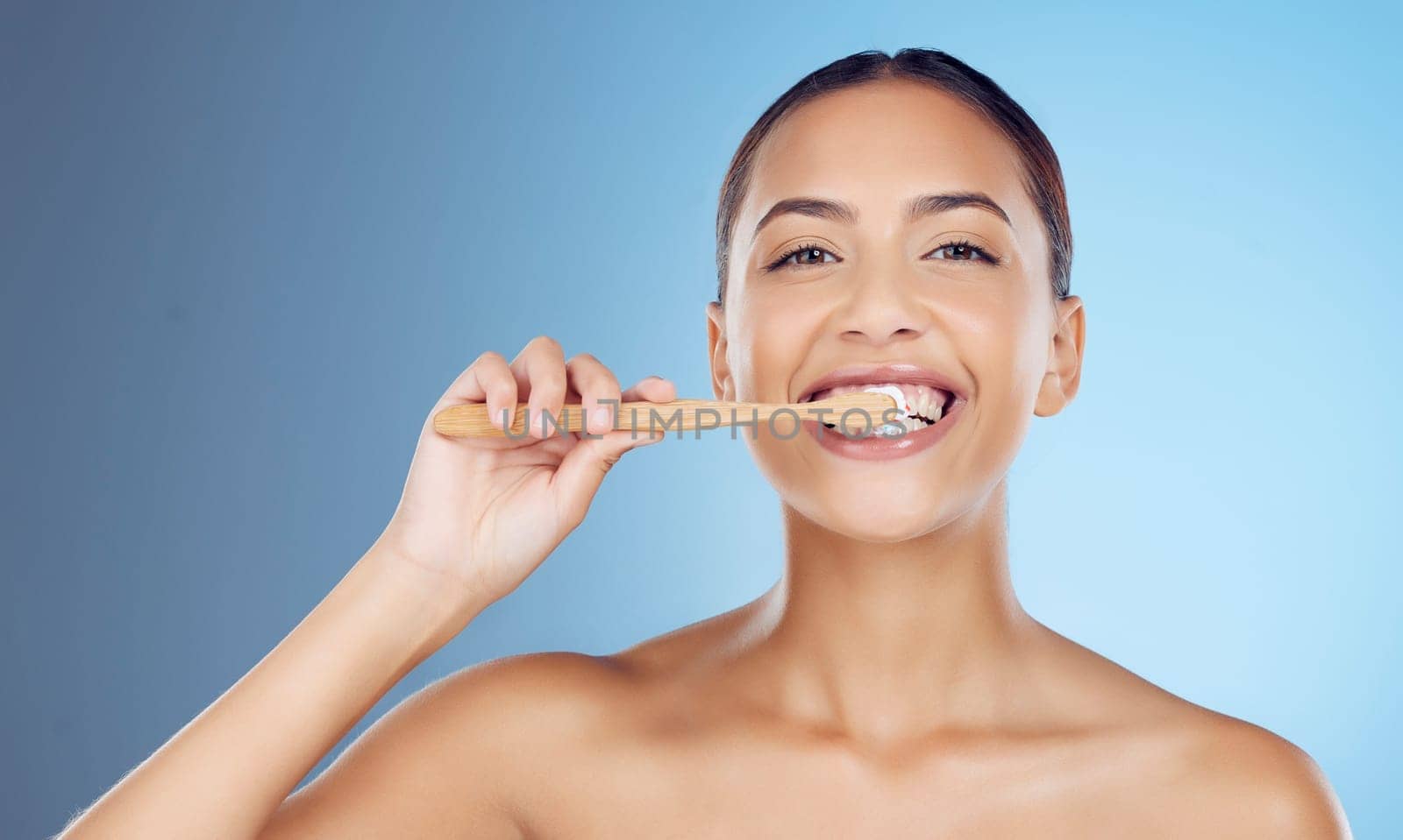 Bamboo toothbrush, toothpaste and portrait of woman for dental wellness, healthy cleaning or model cosmetics. Happy female teeth, eco wooden brush and mouth for smile, face and studio blue background.