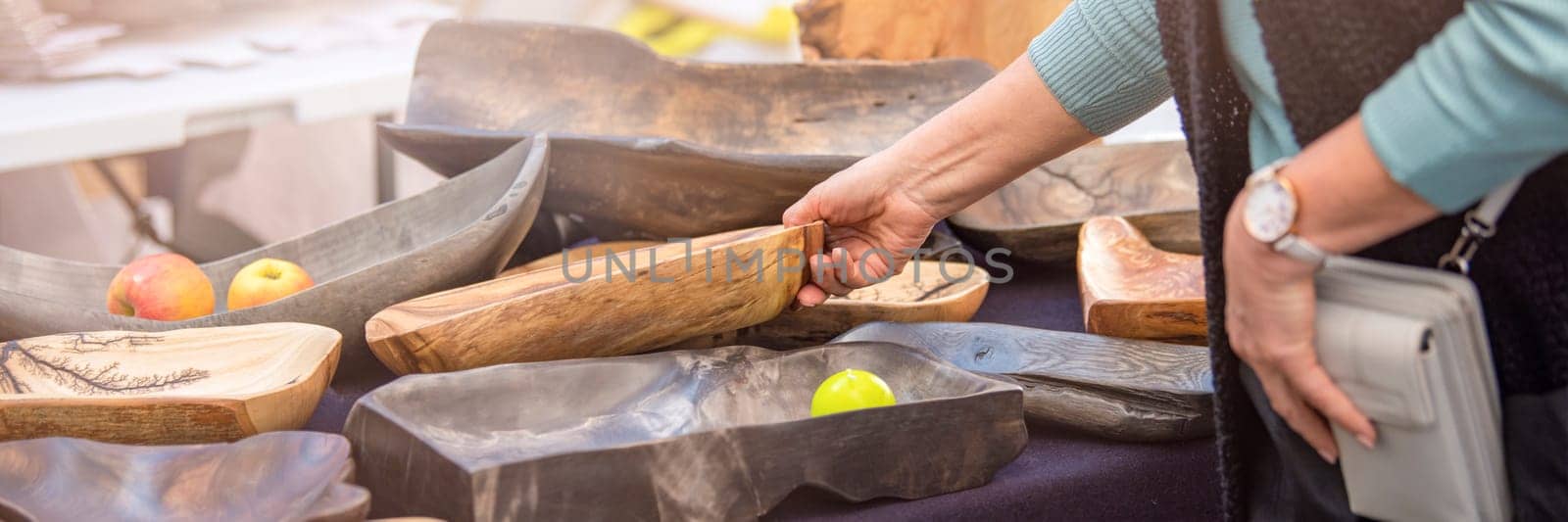 Wooden plate. Large plates and trays are made of exotic woods in different colors, the buyer chooses wooden utensils in the market, the concept of craft and small business by SERSOL