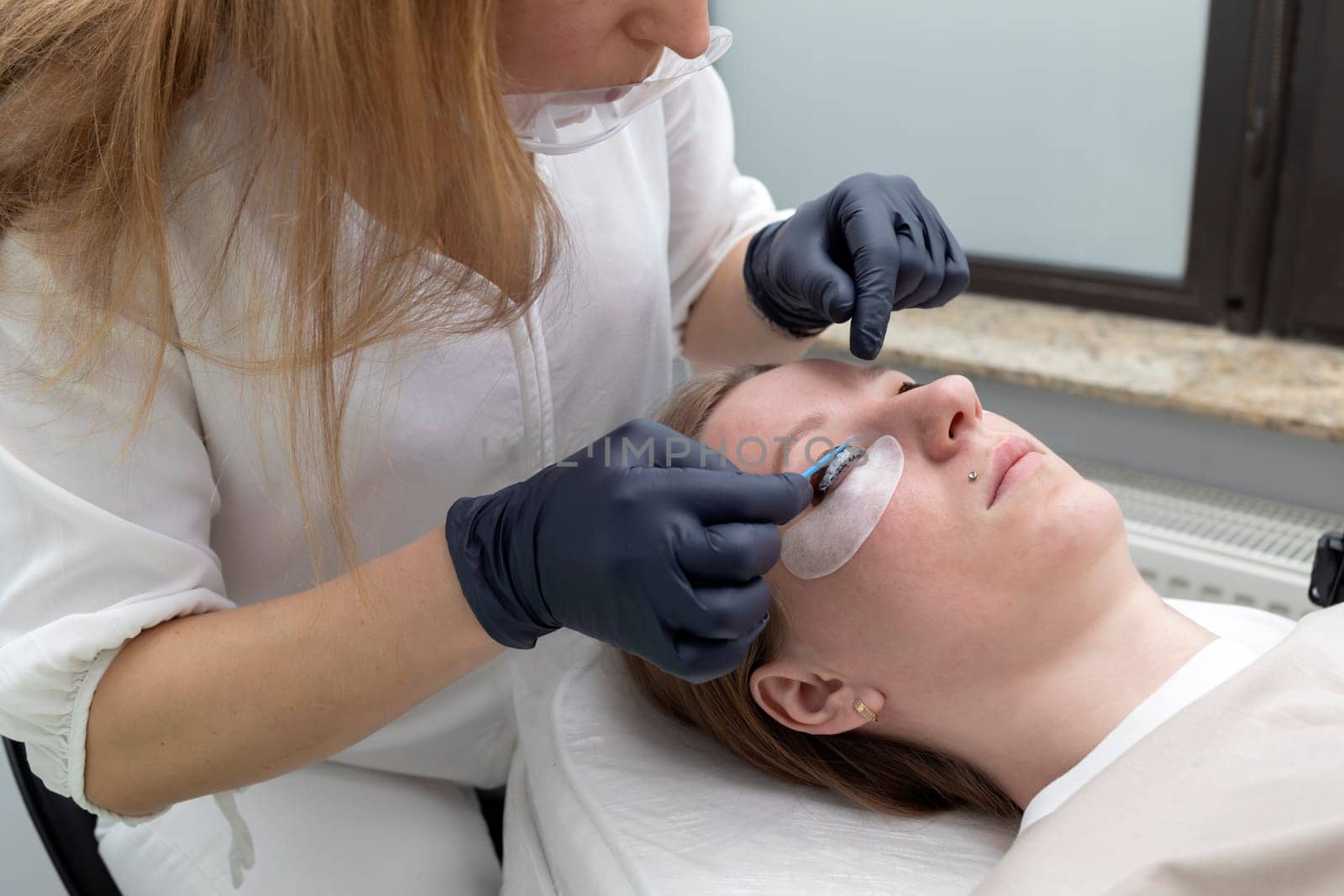 Beautician Applies Lash Lift Lotion On Rolled Hair During Eyelash Lamination Treatment Procedure In Beauty Salon. Curling, Staining, Extension Procedures For Lashes. Horizontal Plane.