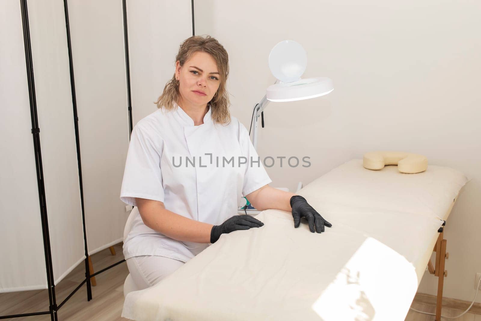 Portrait Of Electrologist, Smiling Beauty Specialist Looking At Camera In Beauty Salon. Authentic Photo Of Aesthetic Specialist Providing Skin Care Services. High quality photo. Horizontal Plane by netatsi