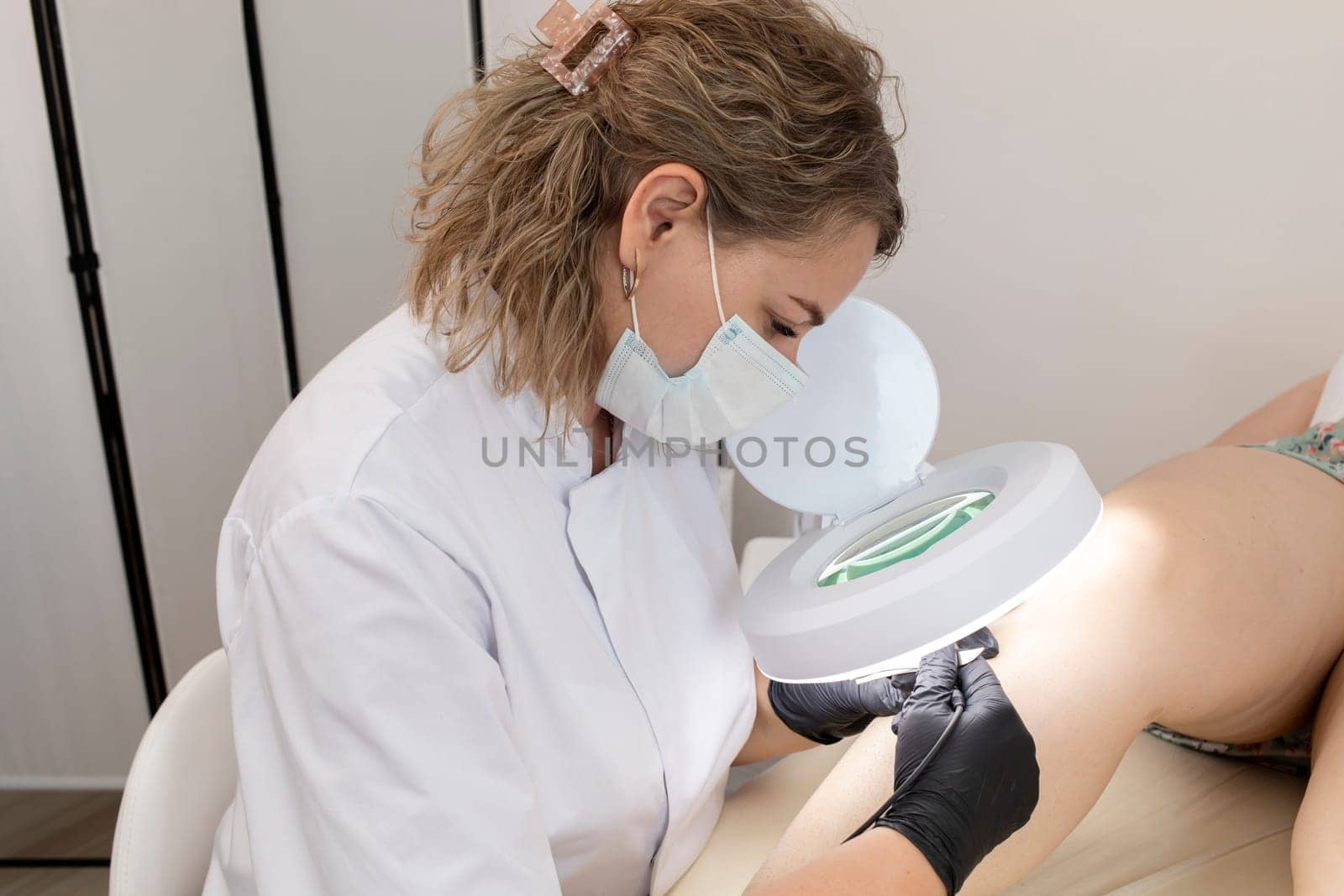 Hirsutism, Excess hair. Female Dermatologist Doing Hair Removal Electrolysis Procedure On Woman's Leg, Shin. Electric Epilation In Beauty Salon. Horizontal Plane. Authentic Photo.