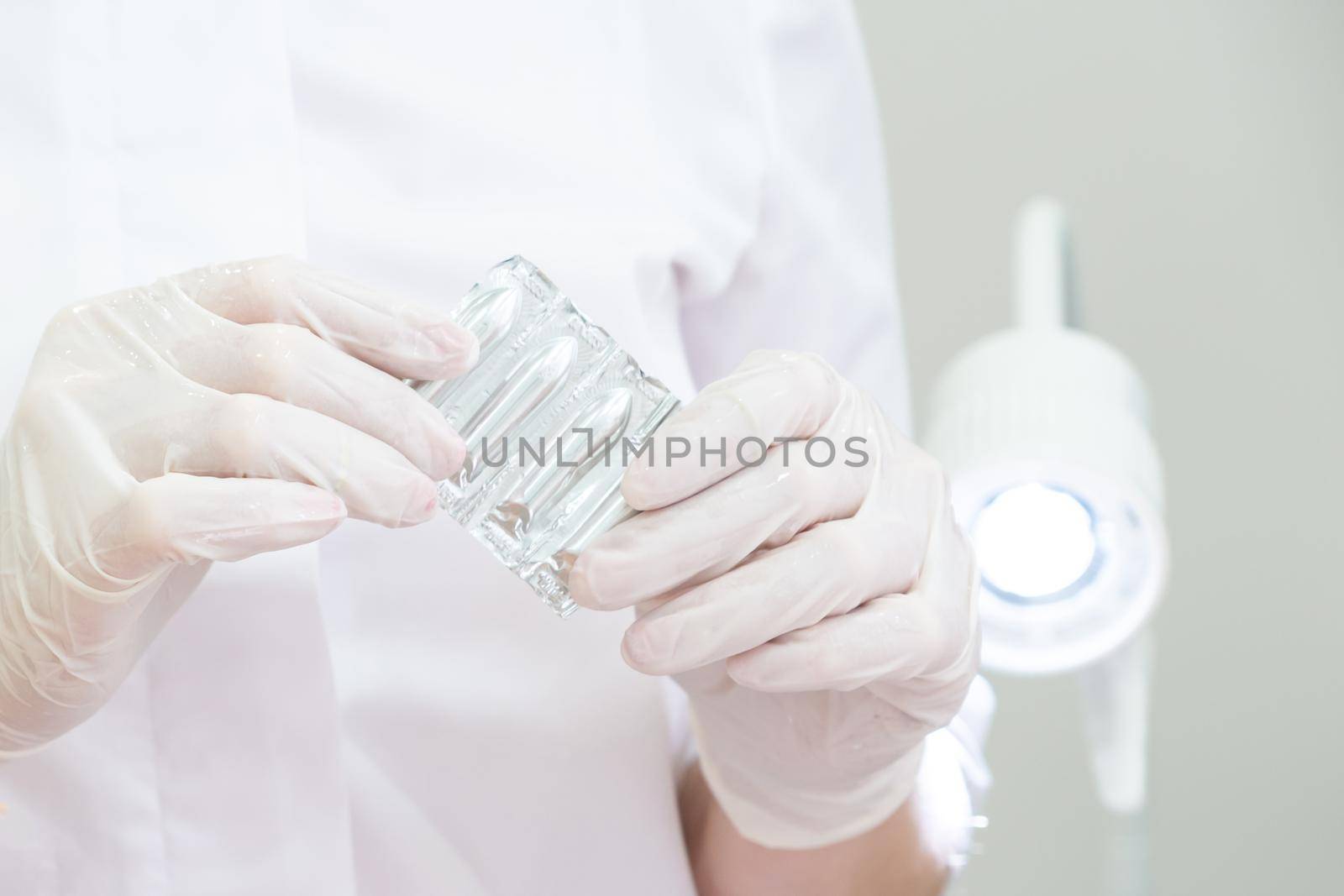 Doctor wearing white medical gloves holding a pack of suppositories