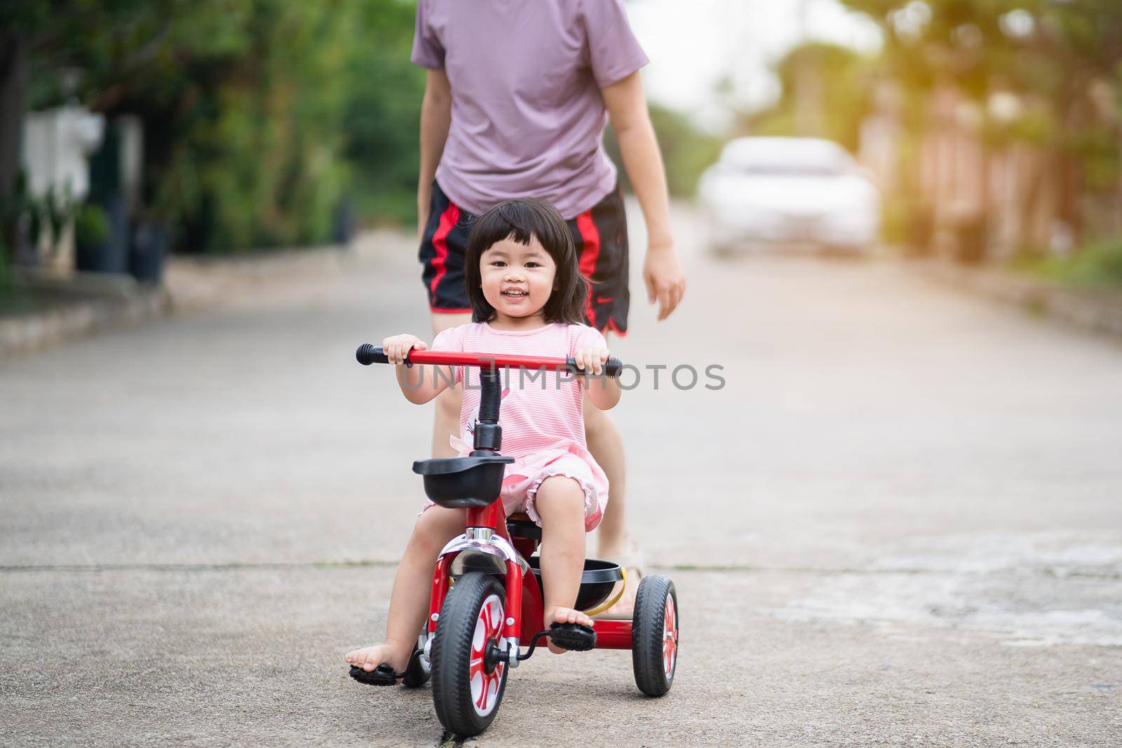 Cute children riding a bike with her mother. Kids enjoying a bicycle ride. by Wmpix