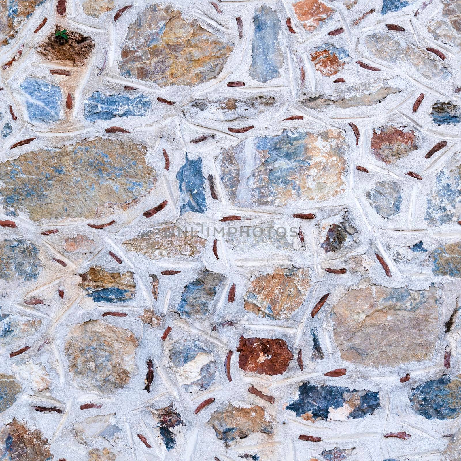 Seamless texture of asymmetric masonry made of multicolored stones. Top view.