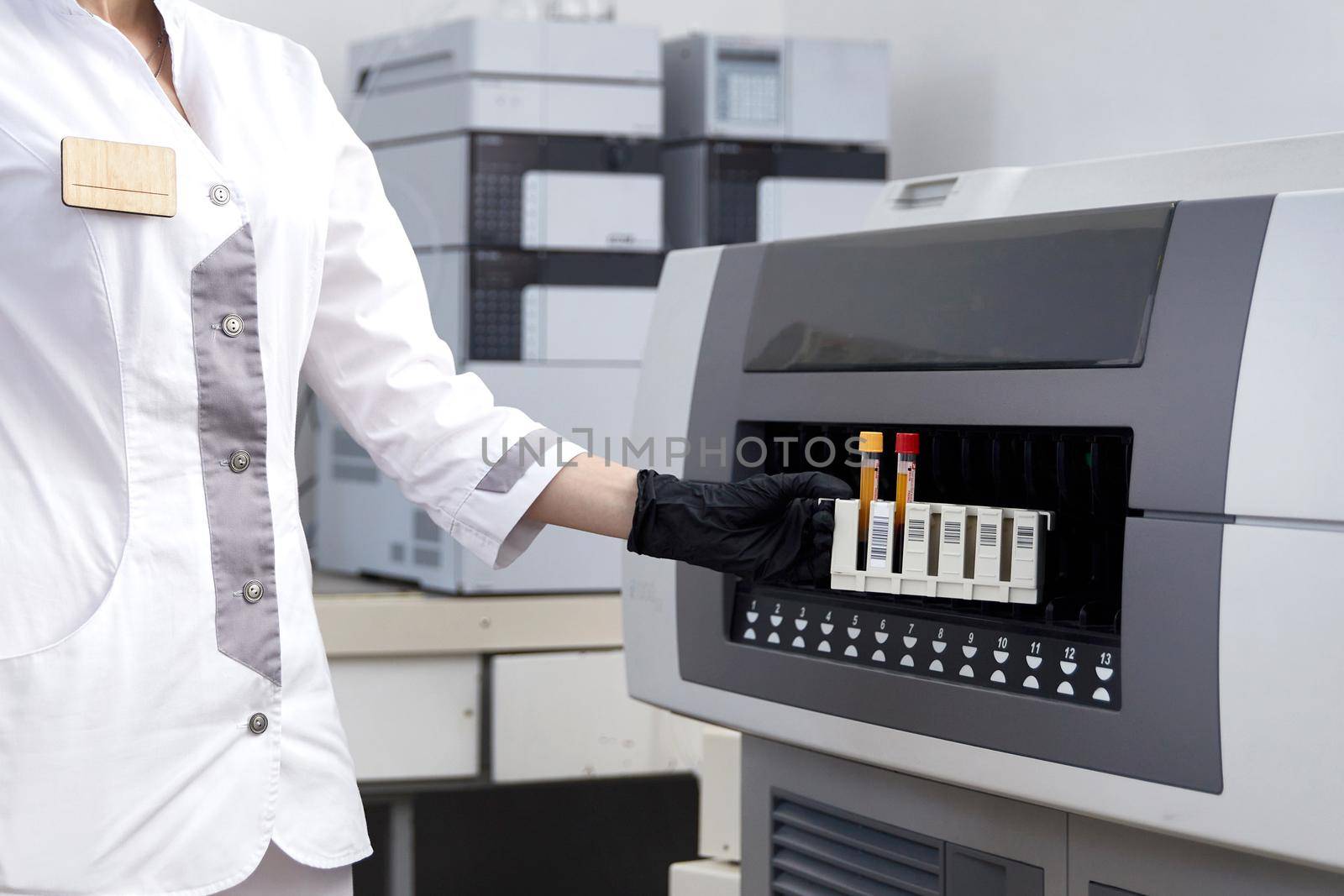 Female Research Scientist Putting Test Tube with Blood Sample into Analyzer Medical Machine. Scientist Works with Modern Medical Equipment in Pharmaceutical Laboratory