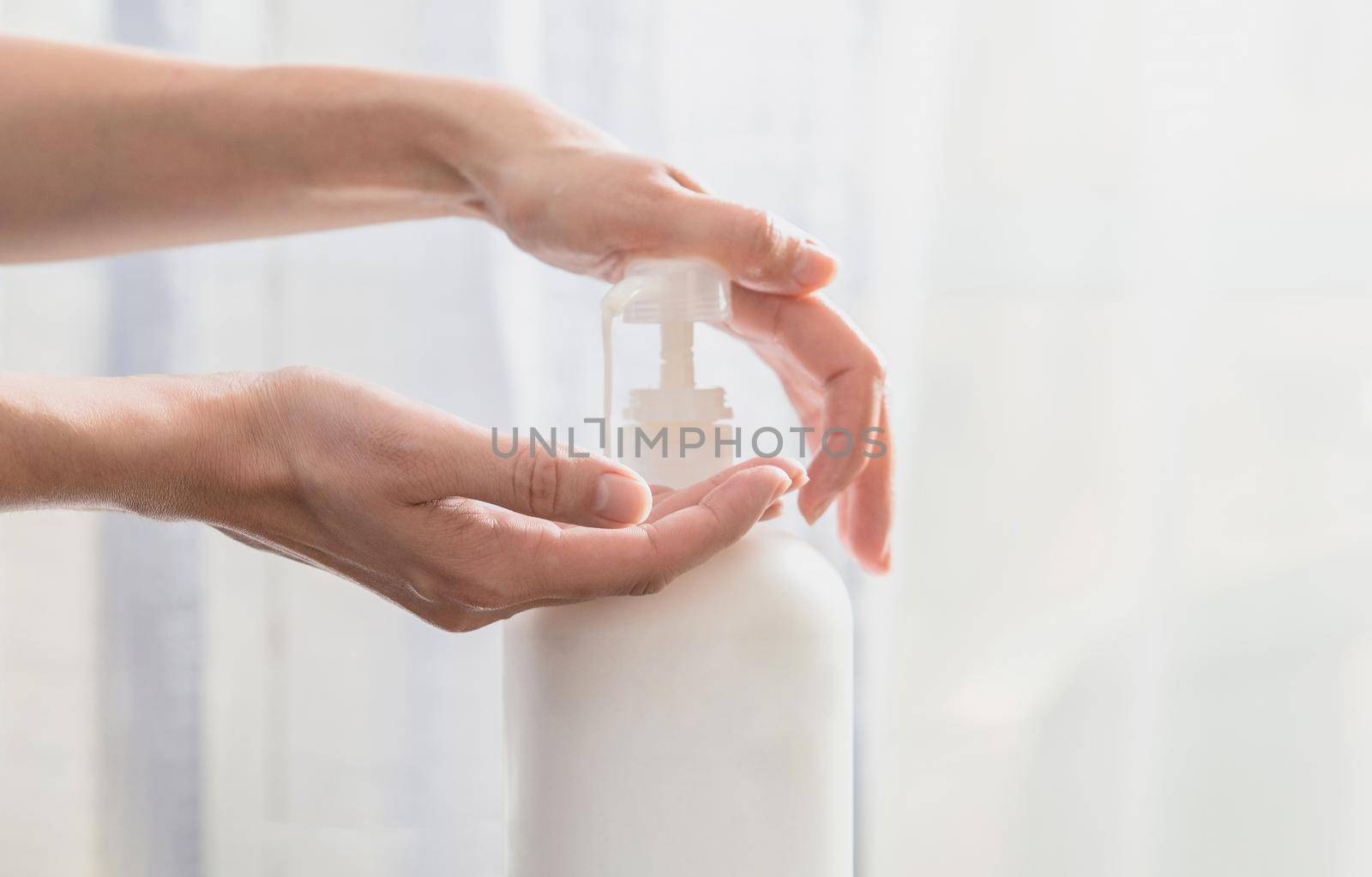 Woman hands pushing pump plastic soap bottle on white background by Mariakray
