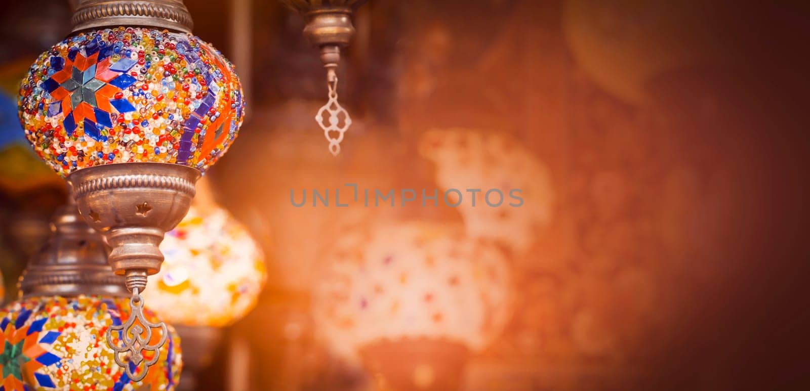 Middle Eastern lambas of different colors and sizes are hanging in the bazaar. Bright traditional Arabic and Turkish lanterns made of metal and glass, inlaid with mosaic details of different colors.