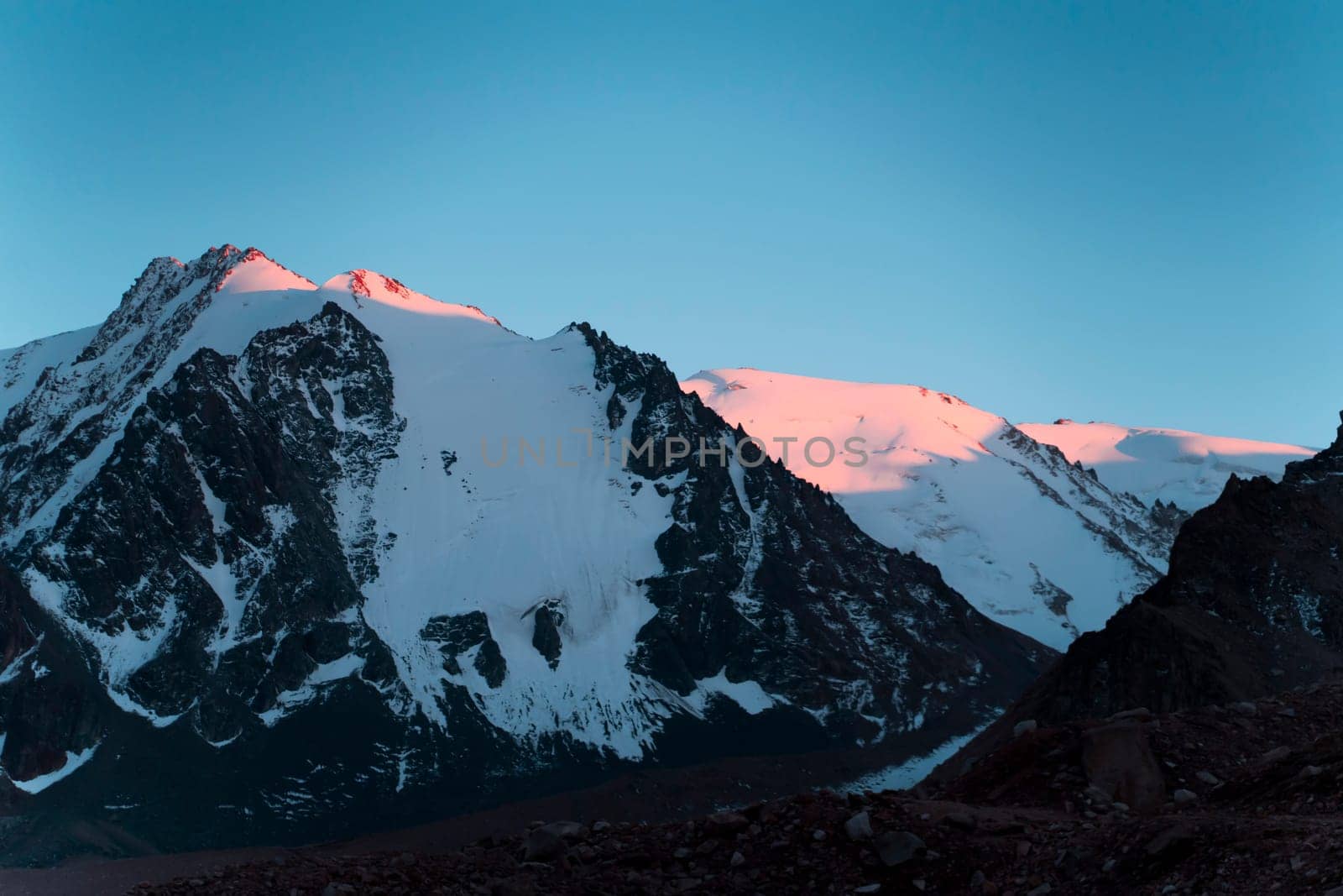 Stunning majestic landscape with snow-capped mountains and glaciers in the last rays of the sun at sunset.