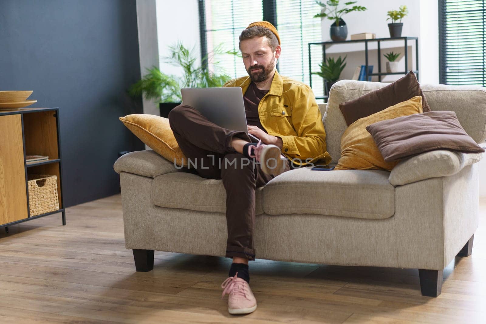 Man sitting at home, engrossed in laptop, types comments in social networks on internet. Man with a unique and eccentric demeanor, giving him appearance of weirdo or crank. . High quality photo