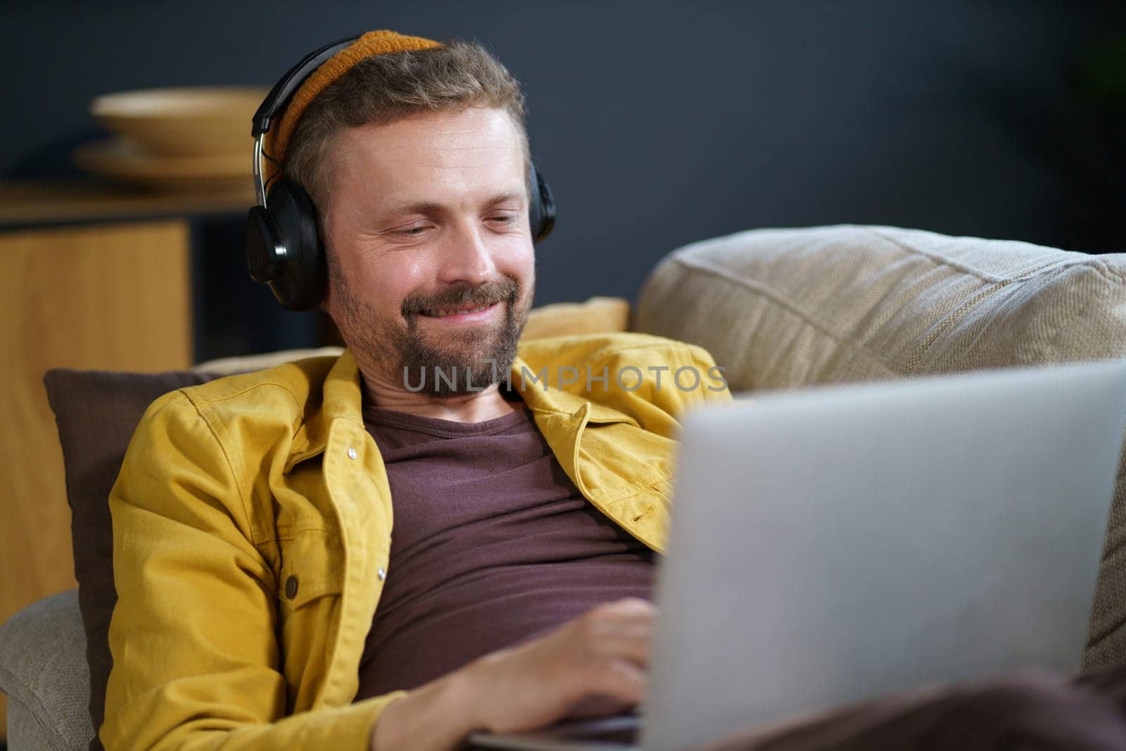Happy student lay on sofa with notebook and engage in search for true internet information. Student's enthusiasm for learning and their commitment to seeking knowledge through online research. . High quality photo