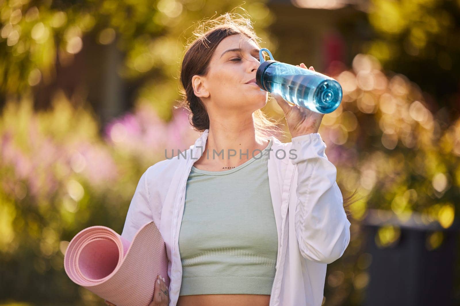 Fitness, woman and water for hydration in yoga for healthy, exercise or workout in the nature outdoors. Female drinking from bottle holding mat for exercising, training and wellness in health sport by YuriArcurs