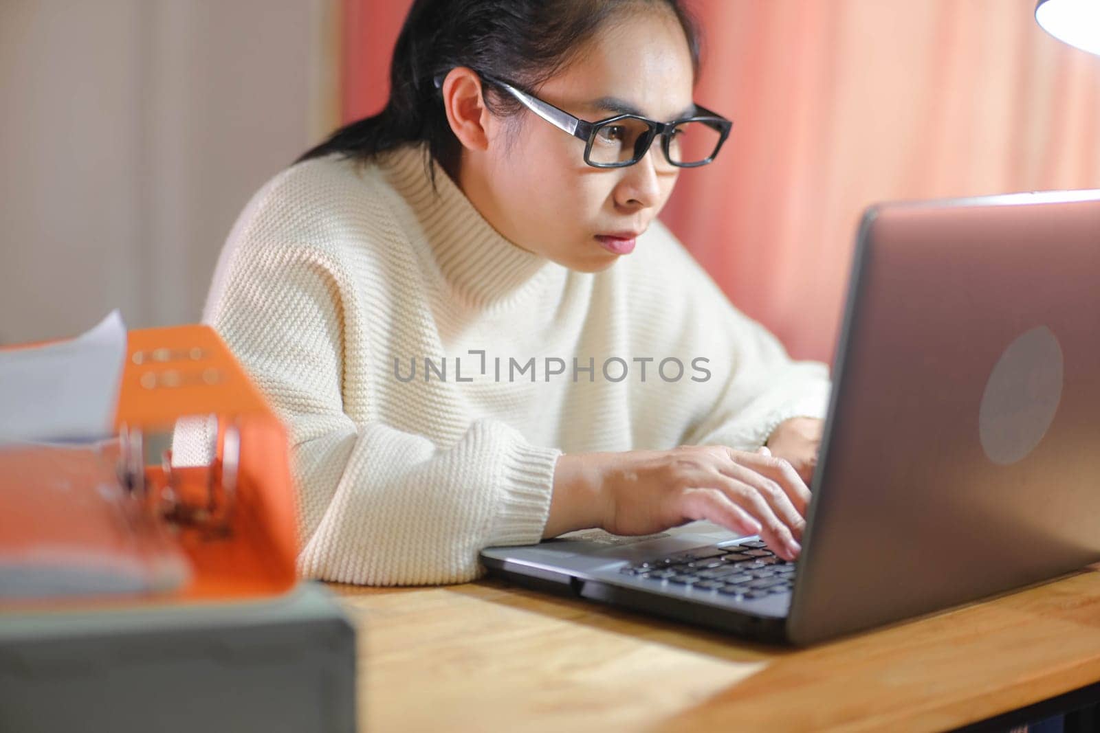 Busy businesswoman working on laptop computer in office. Confident young woman in casual clothes using laptop while working at home. by TEERASAK