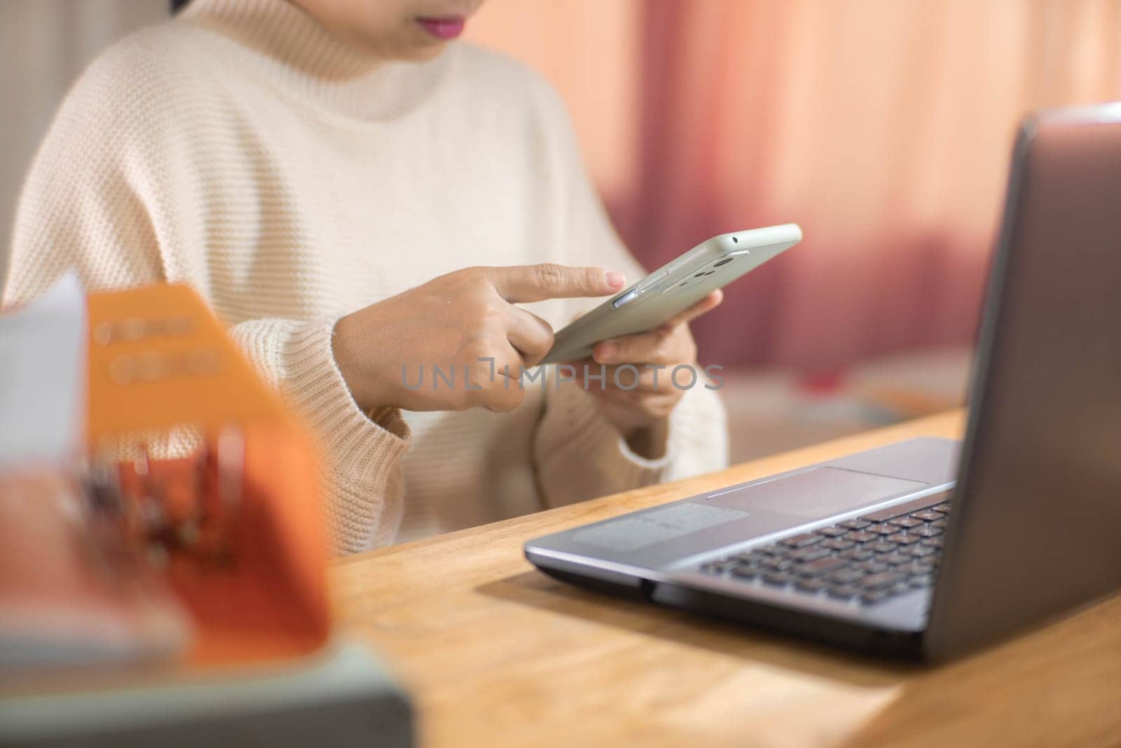 Young Asian woman using smartphone and working sitting in office at home close-up. by TEERASAK
