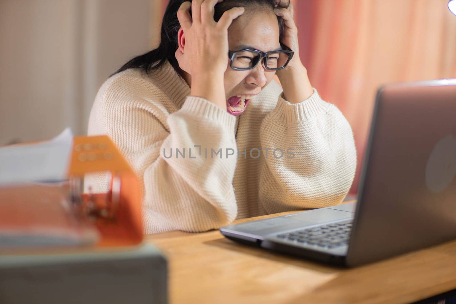 Stressed woman working with laptop in office at home. Busy businesswoman in glasses using laptop sitting in office and doing research.