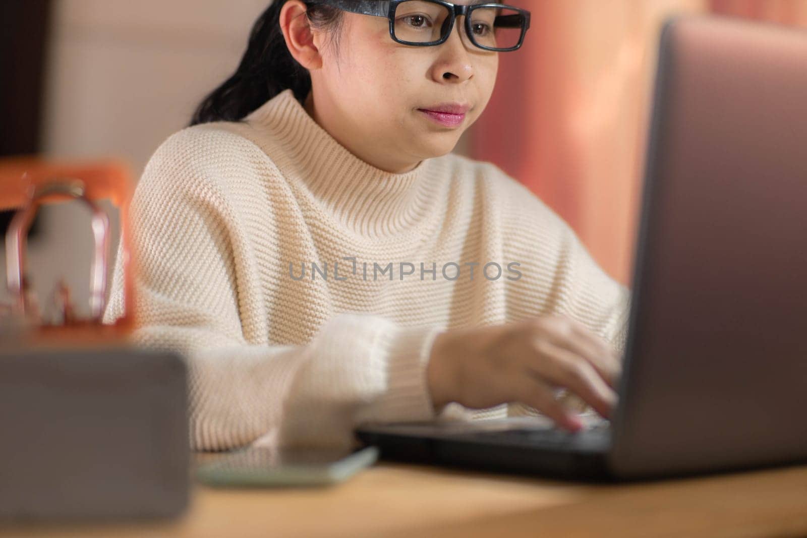 Busy businesswoman working on laptop computer in office. Confident young woman in casual clothes using laptop while working at home. by TEERASAK