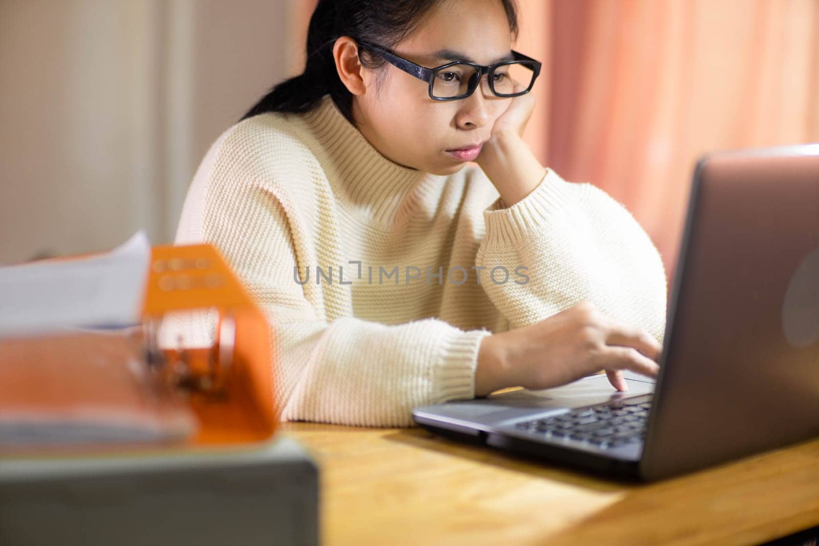 Bored woman working on laptop in workplace at home. Businesswoman in glasses using laptop sitting in office and doing research. by TEERASAK
