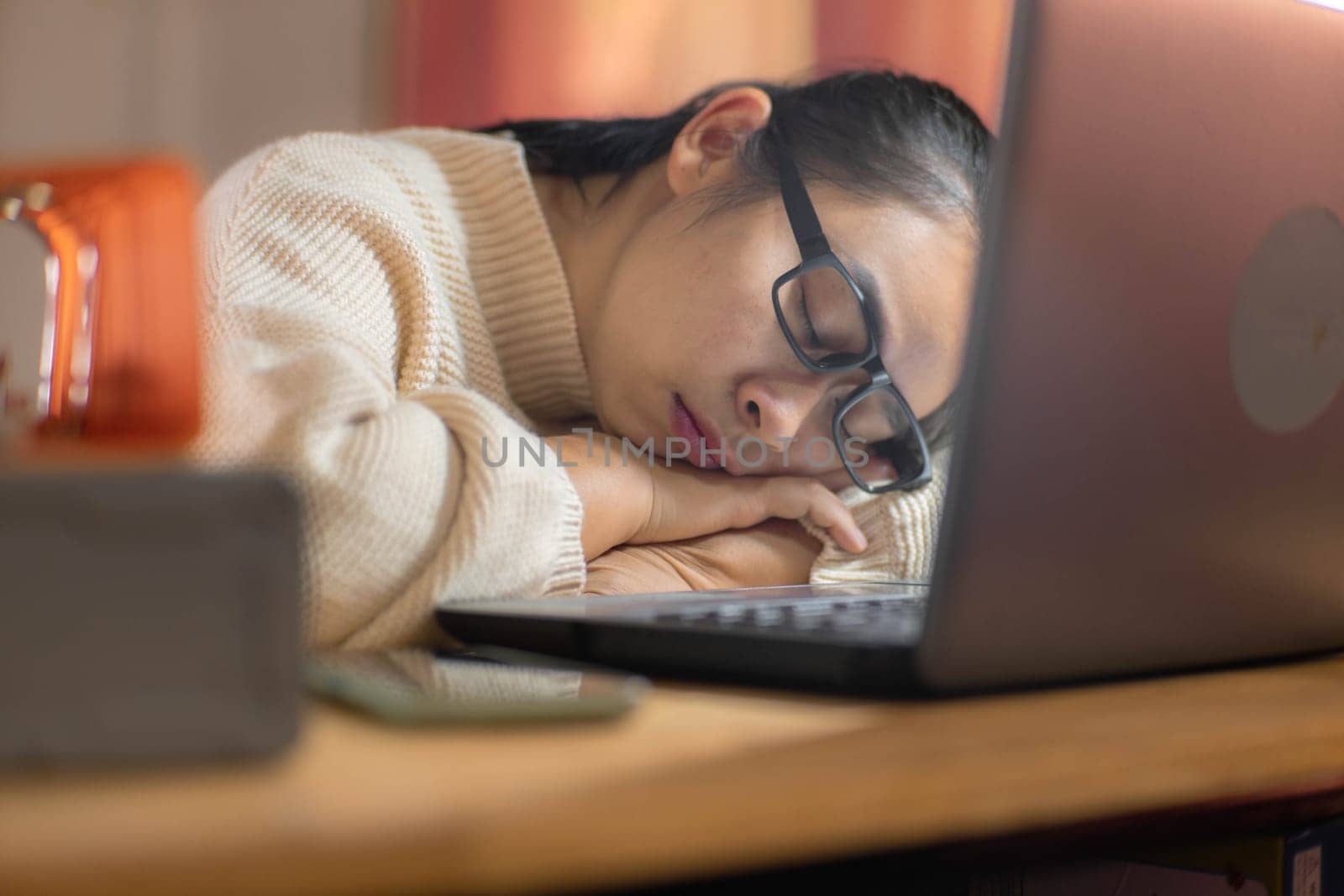 Woman sleeping with laptop in home office after long hours of work. by TEERASAK