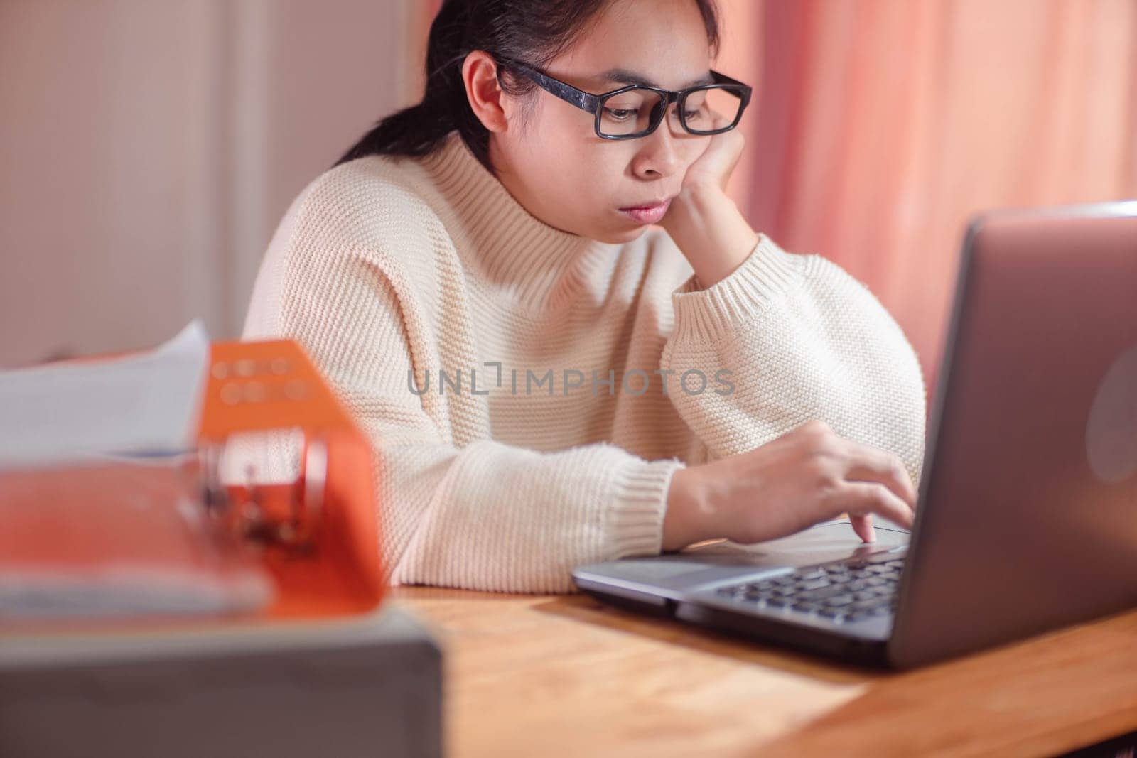 Bored woman working on laptop in workplace at home. Businesswoman in glasses using laptop sitting in office and doing research.