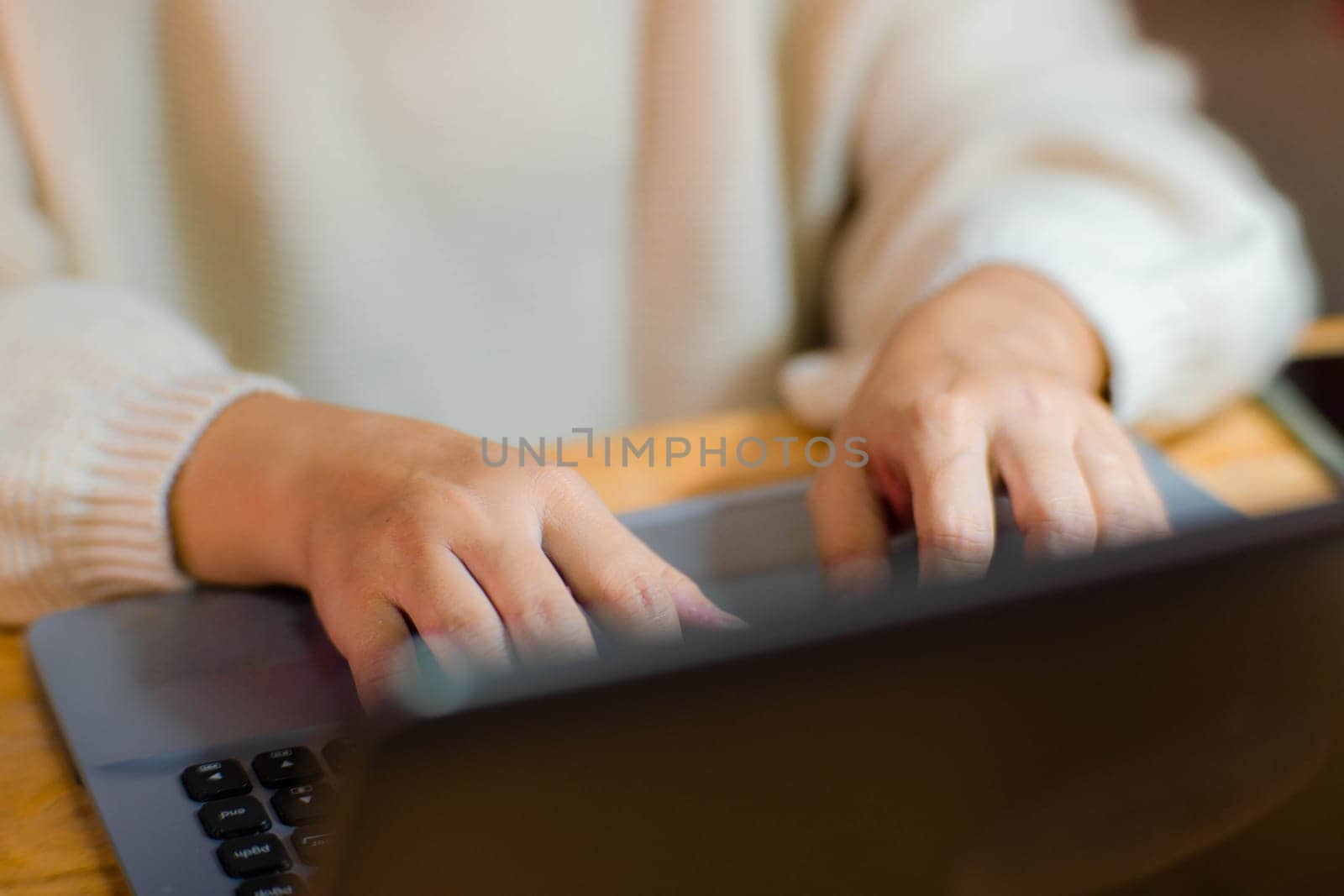 Woman sitting at desk and working on laptop in office at home close-up. Close up of woman hand using laptop sitting in office and doing research. by TEERASAK