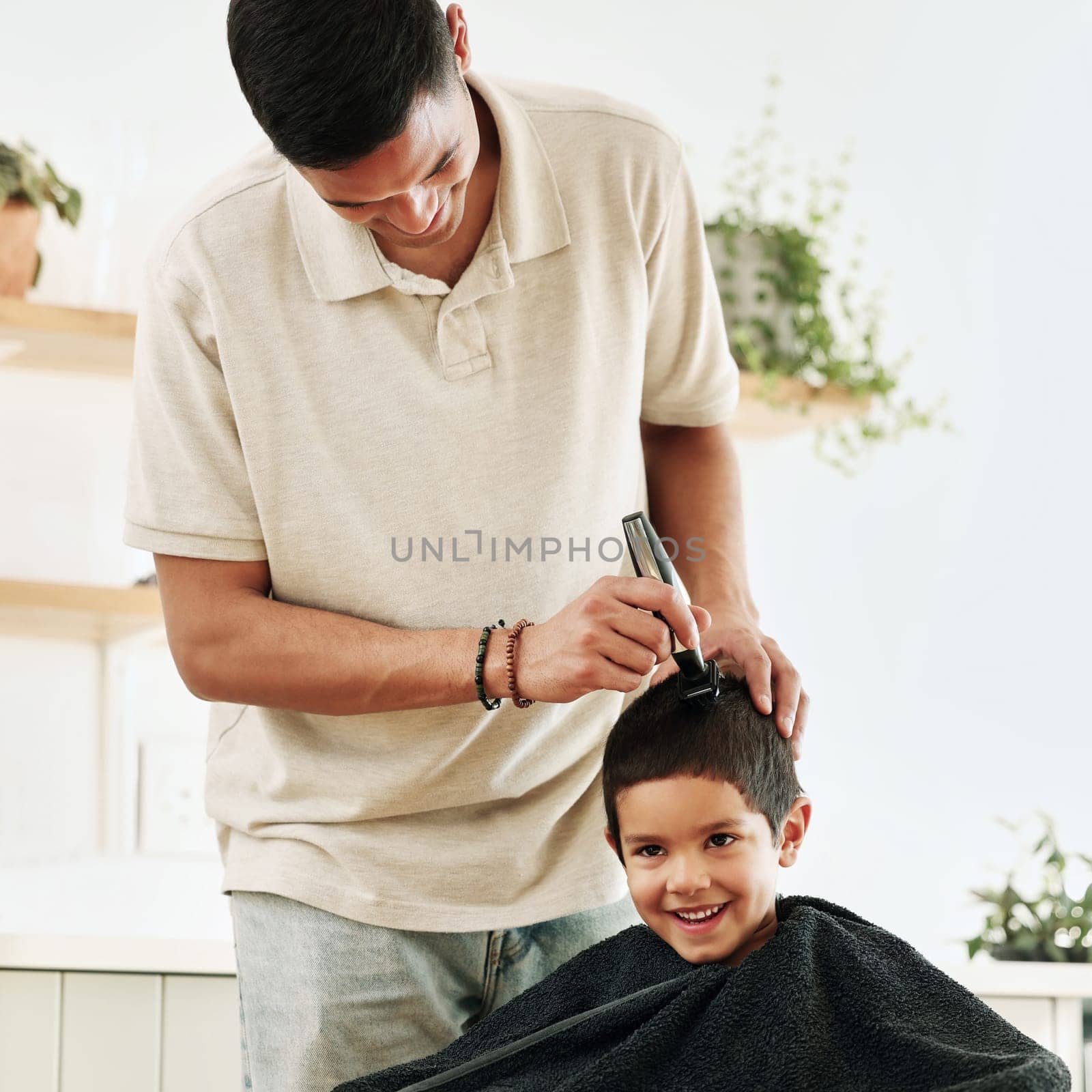 Family, children and haircut with a father shaving the hair of his son together in the home for grooming. Kids, barber and hairstyle with a man cutting the head of his son as a hairdresser in a house.