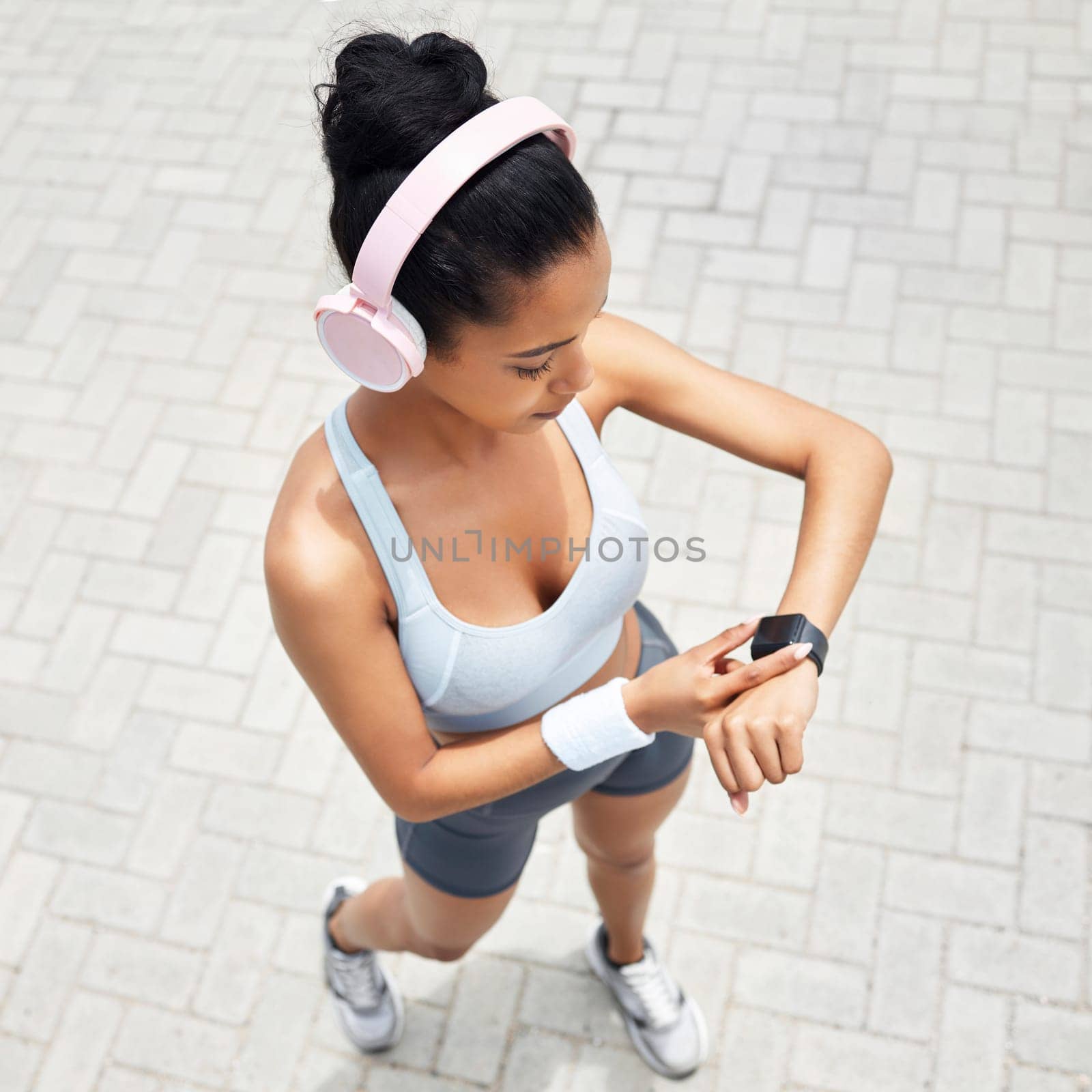 Fitness, woman and watch of runner time monitoring health, performance and distance above outdoors. Active female checking wrist app after a run outside listening to music for training and exercise by YuriArcurs