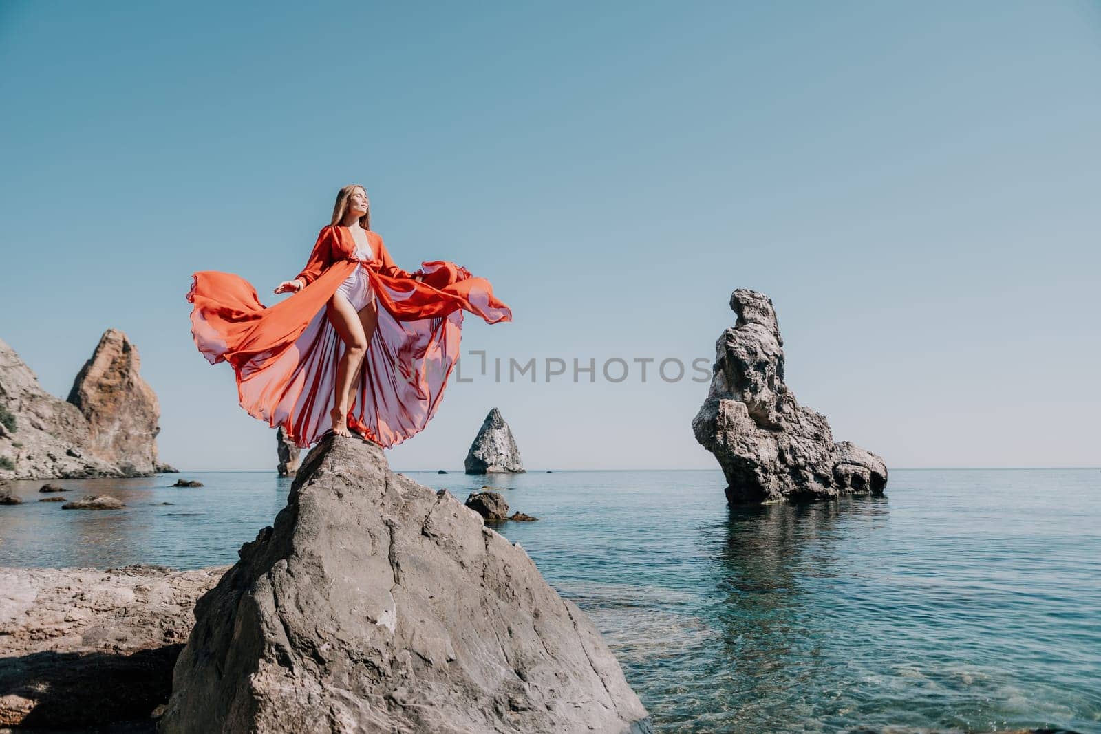 Woman travel sea. Happy tourist taking picture outdoors for memories. Woman traveler looks at the edge of the cliff on the sea bay of mountains, sharing travel adventure journey.