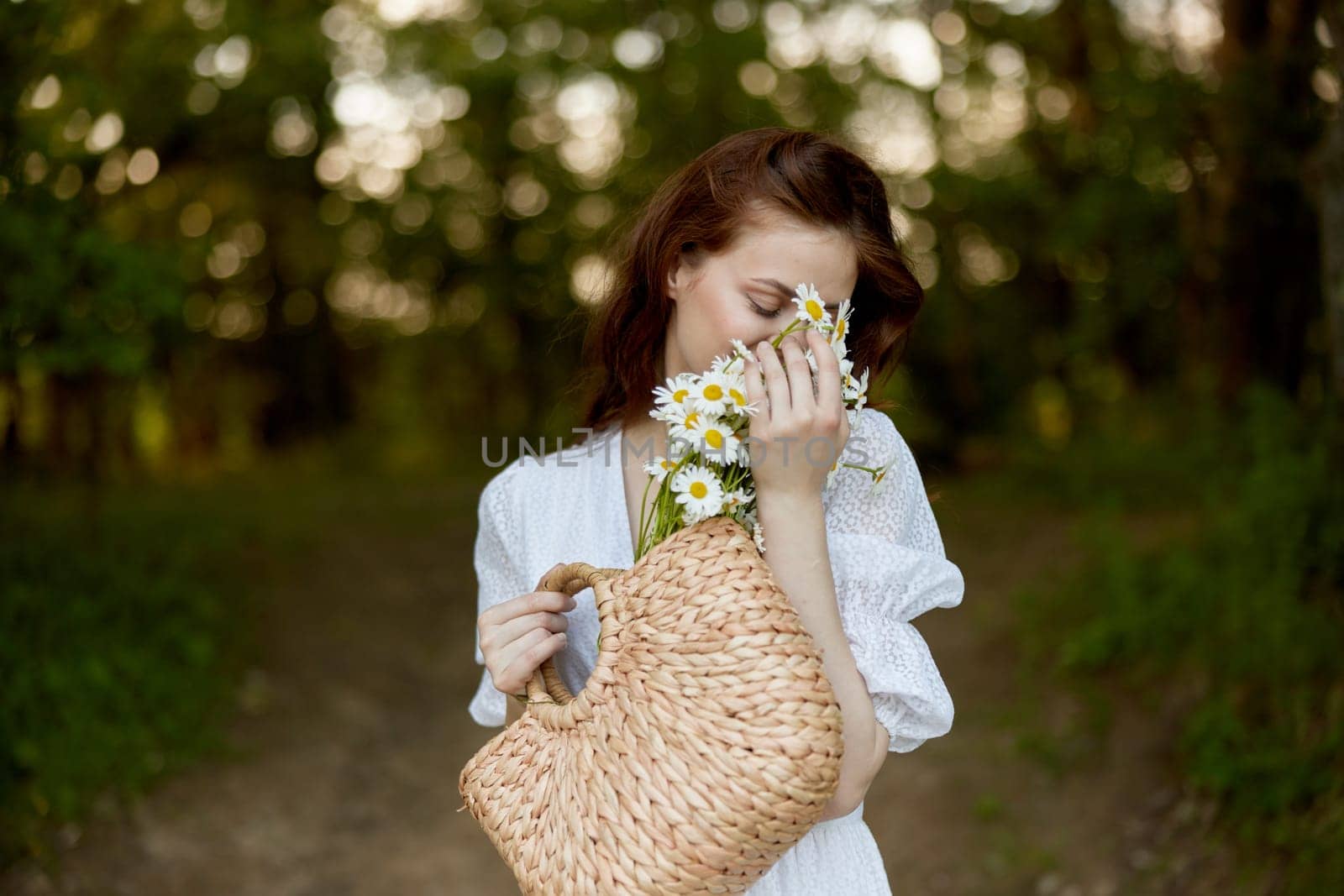 close portrait of a happy, red-haired woman with a wicker basket full of daisies in nature by Vichizh