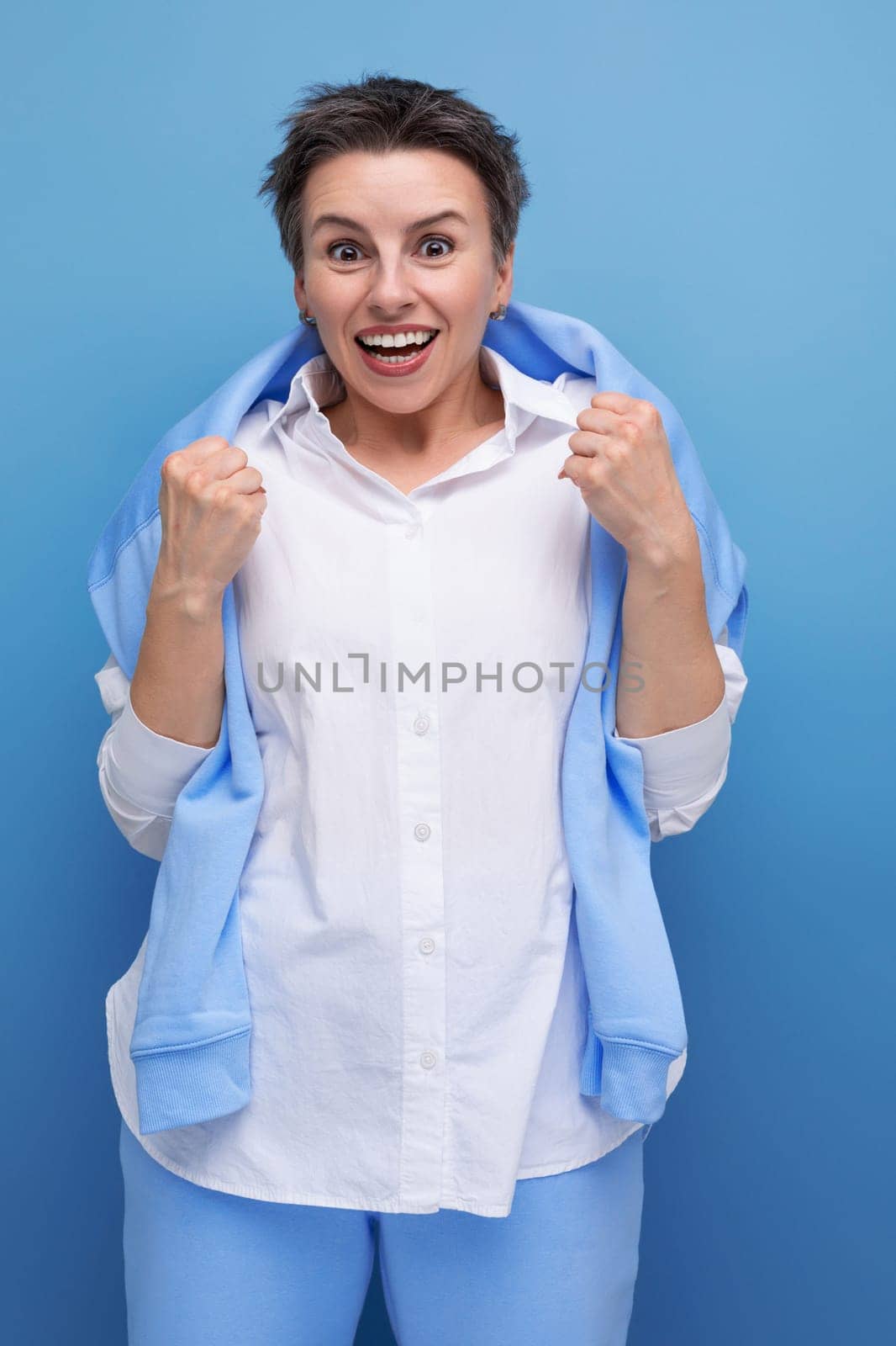 vertical photo of a stylish fashionable young lady with tousled hair in a white shirt in an informal setting.