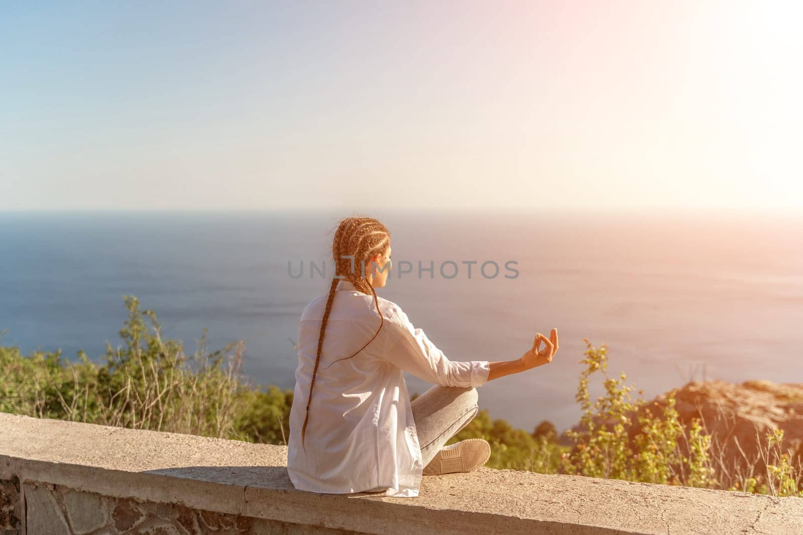 Yoga woman mountains. Profile of a woman doing yoga in the top of a cliff in the mountain. Woman meditates in yoga asana Padmasana by Matiunina