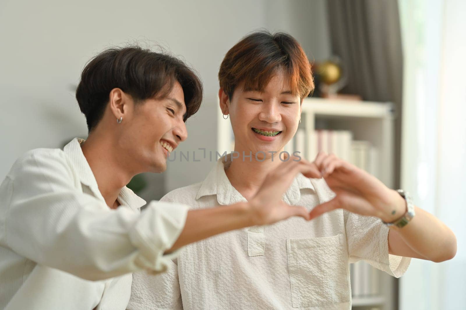 Affectionate romantic male gay couple making heart with their hands. LGBT, love and lifestyle relationship concept.