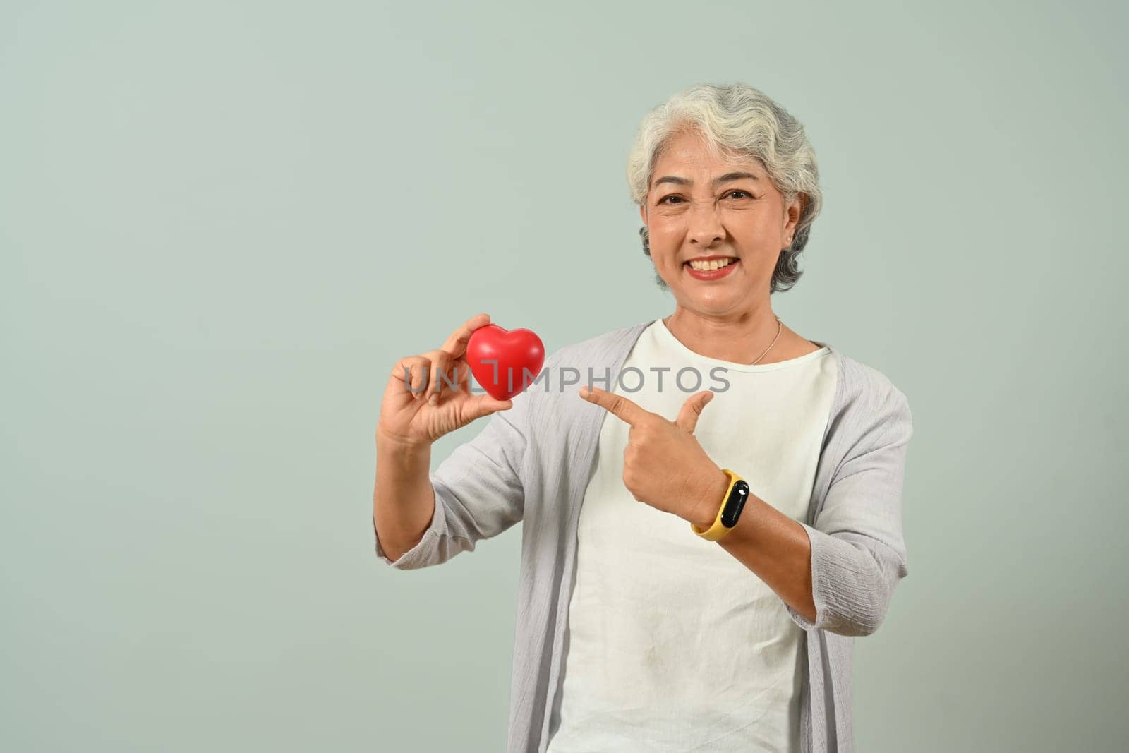 Portrait of attractive senior woman holding red heart in her hands. People, aged people and Healthcare concept.