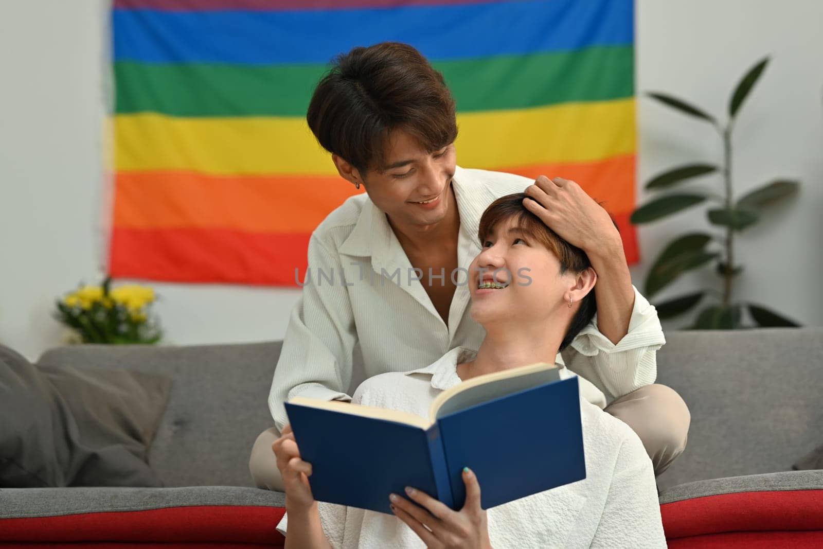 Serene homosexual couple reading book, spending time together on weekend. LGBTQ people lifestyle and love emotion.