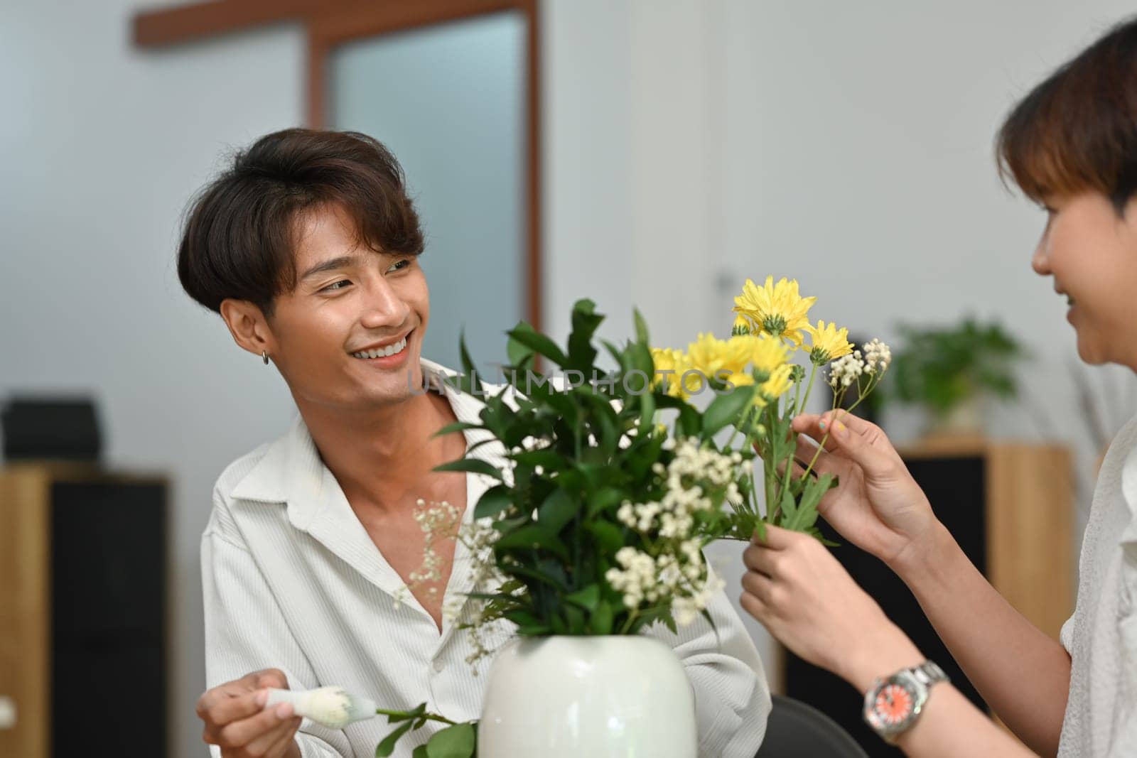 Cheerful gay couple arranging flowers, spending good time together at home. LGBT, love and lifestyle relationship concept.