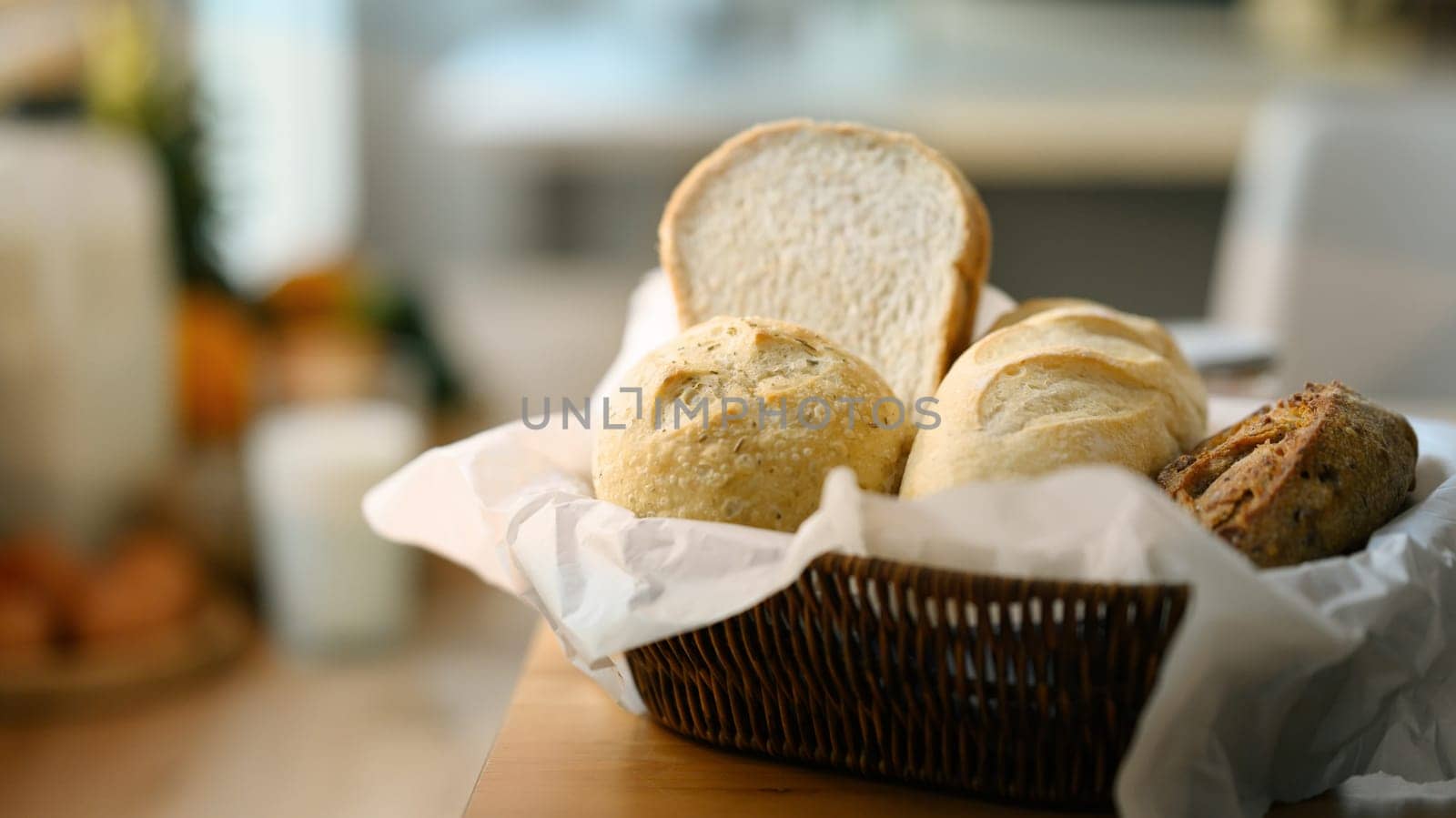 Fresh homemade bread in basket on wooden table in kitchen. Healthy eating and traditional bakery concept.