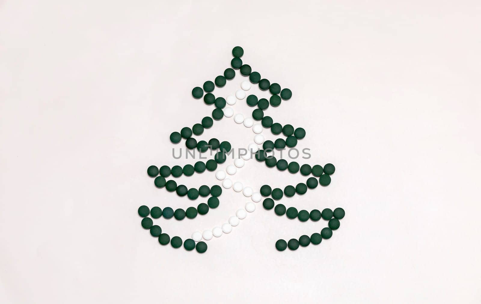 White background, medicine mockup, Christmas tree made of green white pills,tablets,vitamins spirulina. Merry Christmas, Happy New Year concept, harmacy postcard,flatly, top view,copy space Horizontal