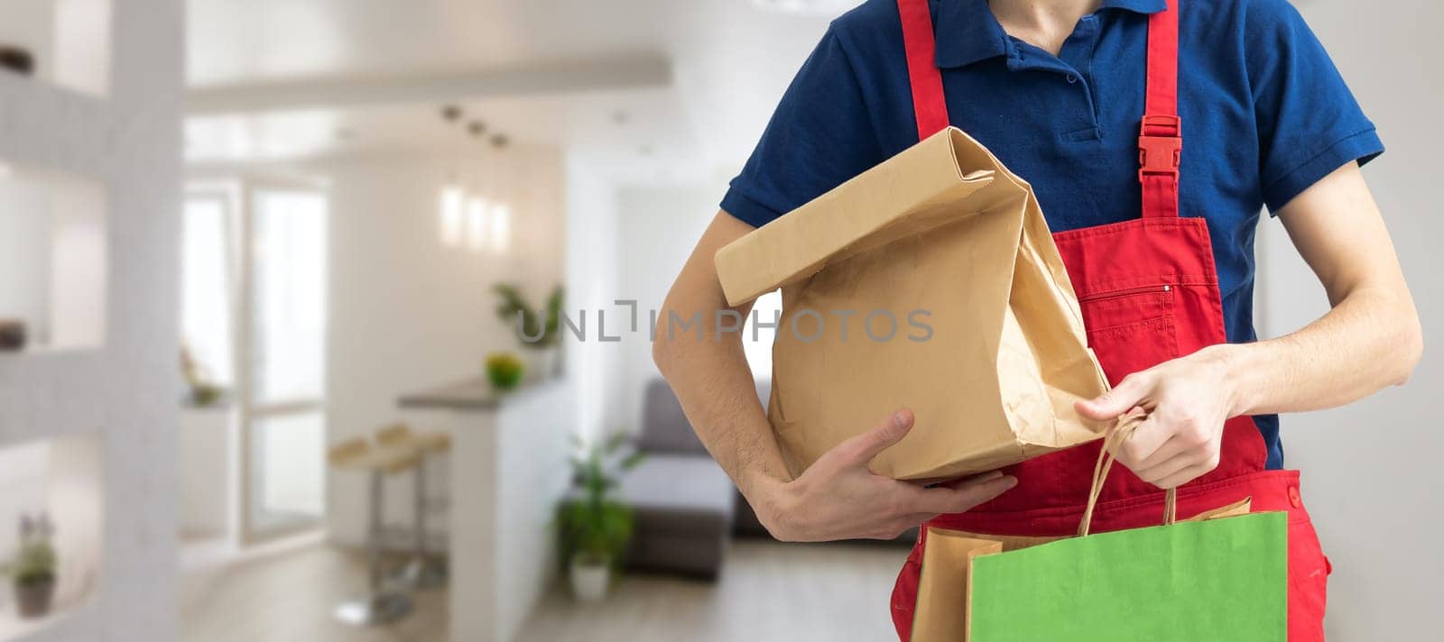 box with fast food being carried by delivery man in uniform for one of clients.