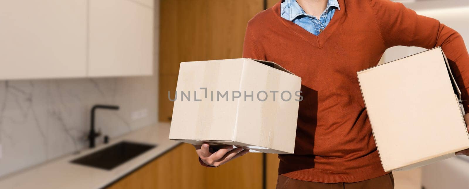 Man lifting cardboard boxes in apartment interior