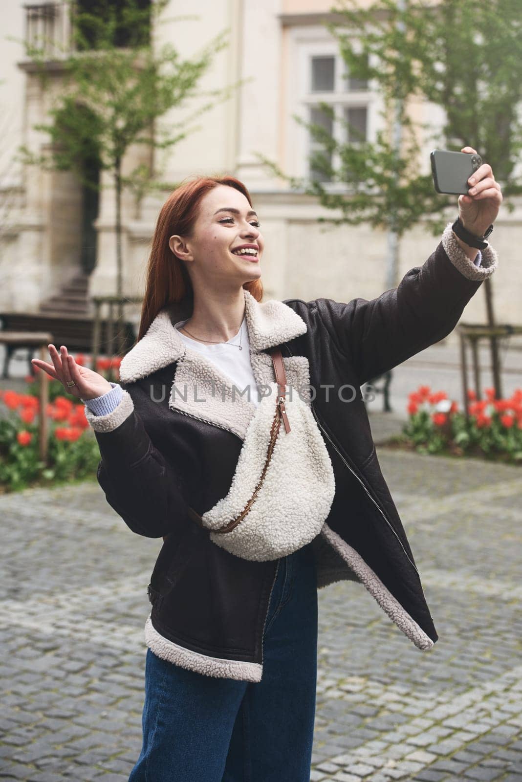 happy woman communicates with friends via video link outdoors on an old town street by Ashtray25